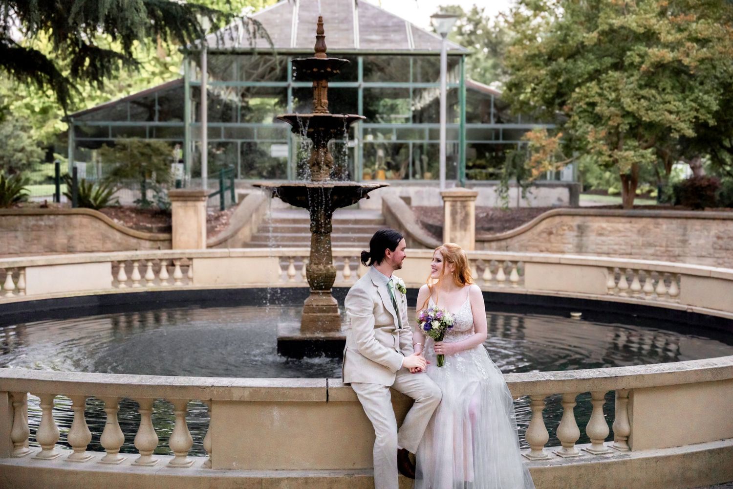 Romantic wedding photoshoot at a grand stone terrace with ornate balustrades and lush garden surroundings.