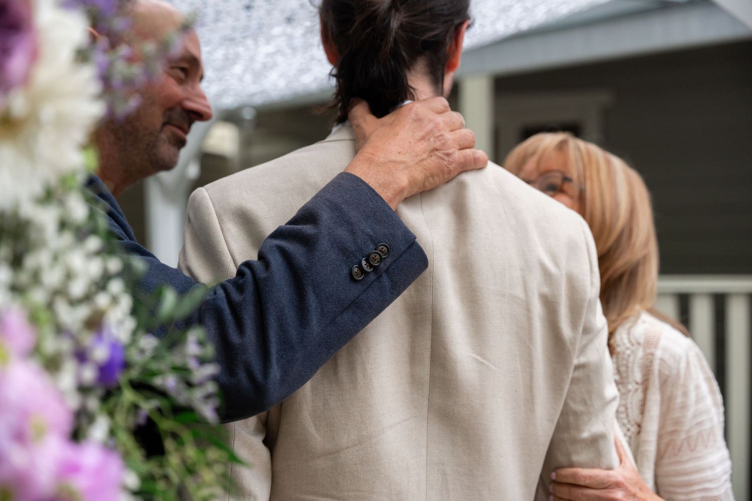 Wedding guests and couple gathered under umbrellas during an outdoor ceremony.