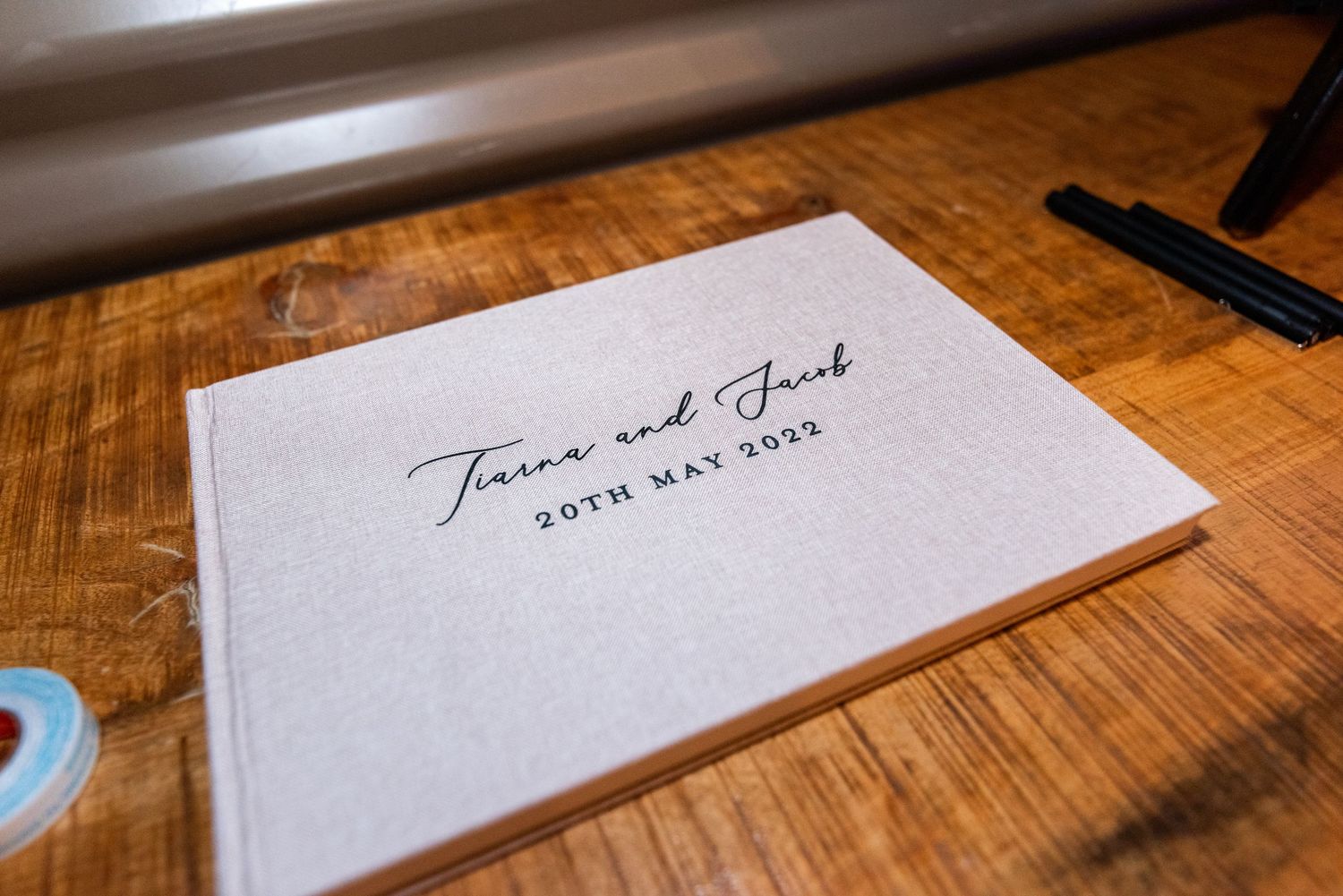 Wedding guest book or document signing pages displayed on wooden table surface.