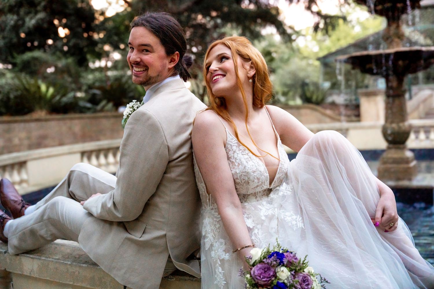 Wedding couple poses together outdoors by a pool with elegant landscaping.