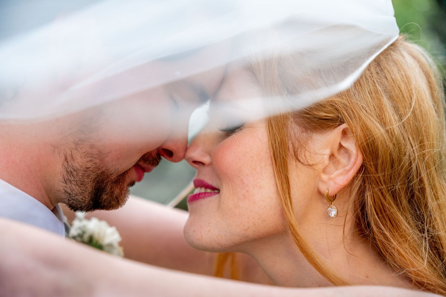Romantic close-up of bride and groom sharing an intimate moment under her flowing veil.