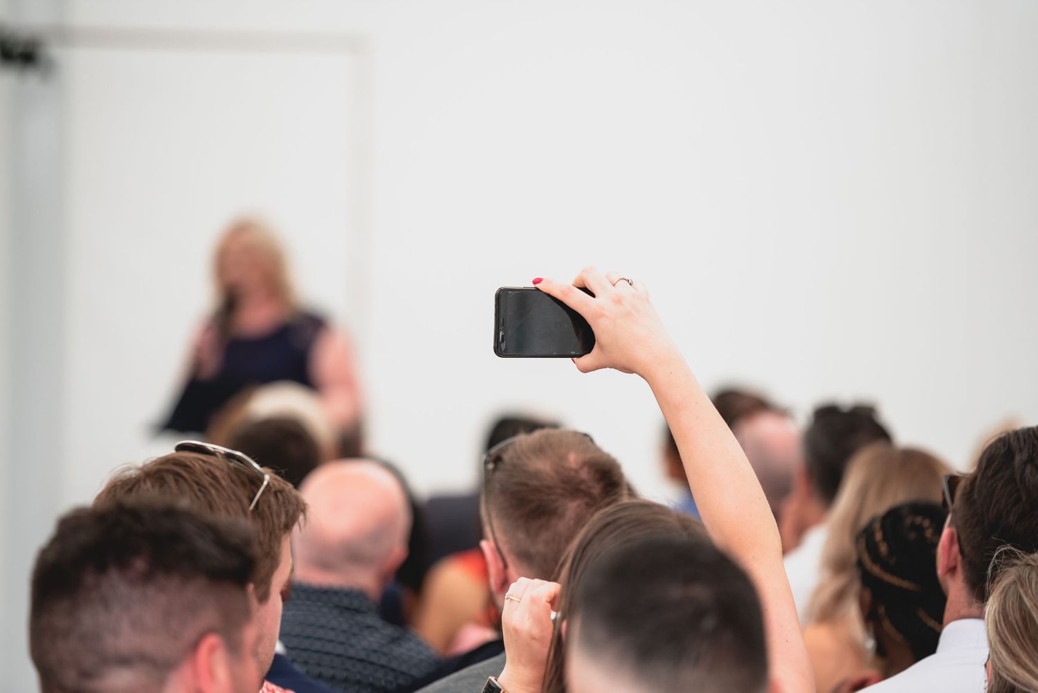 A crowd of people raise their hands during a meeting or conference session.