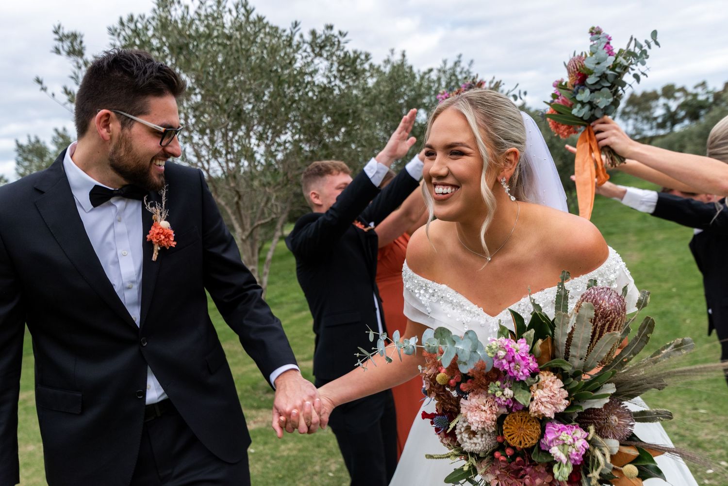 Wedding party celebrating outdoors with joyful expressions and colorful bouquets.
