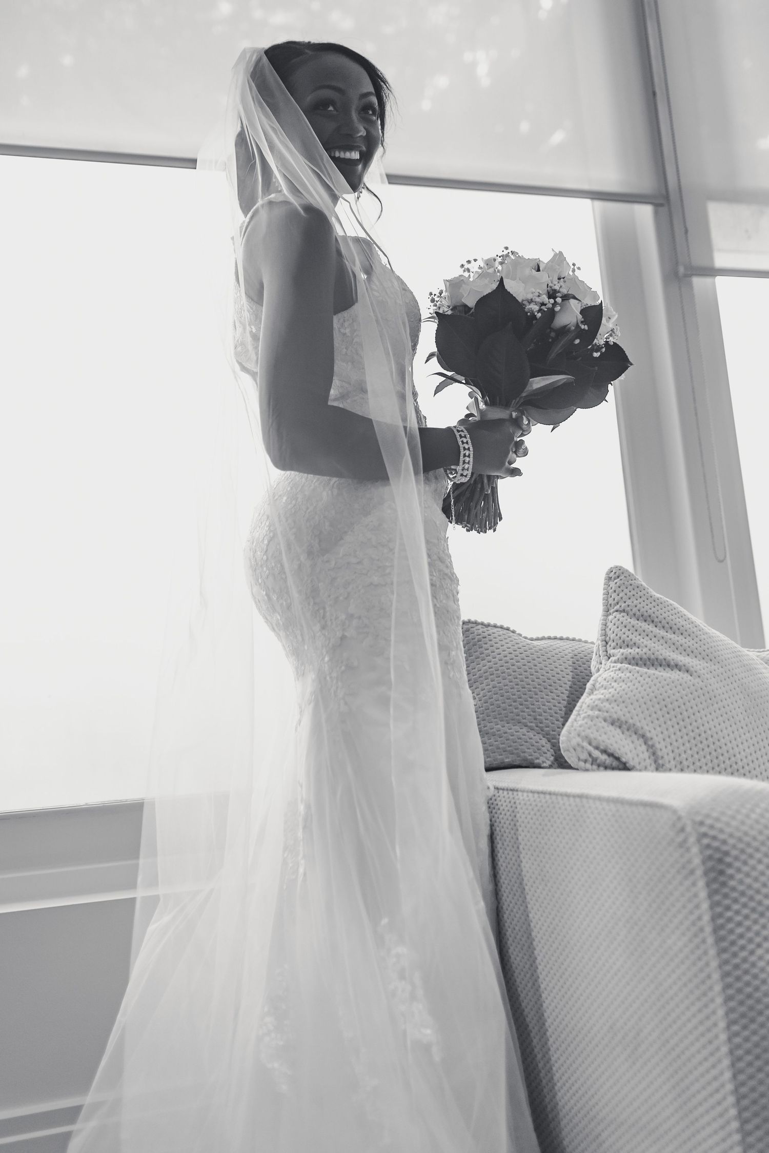 Black and white collage of a bride in a flowing white wedding gown and veil holding a bouquet near bright windows.
