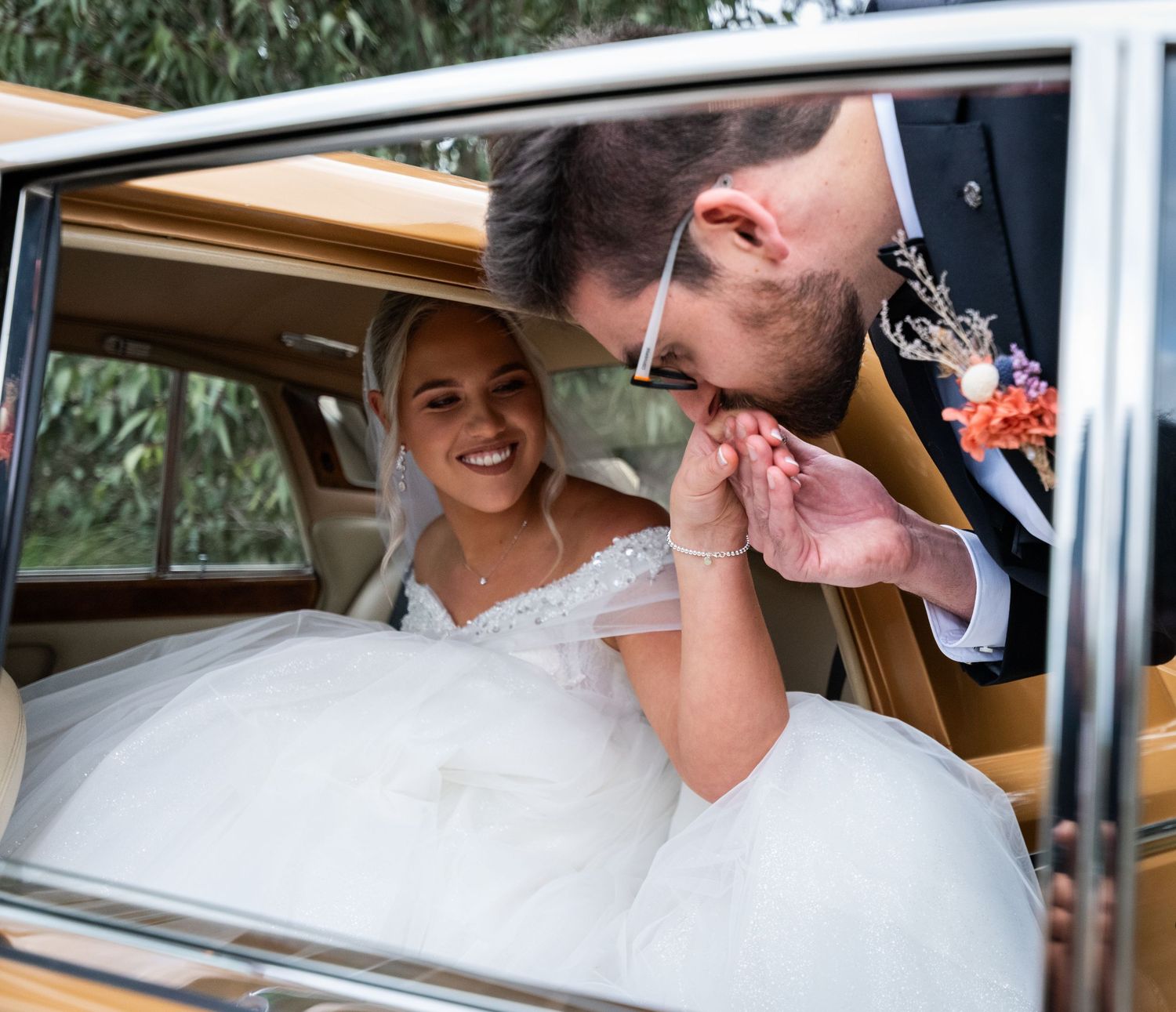 Couple shares tender moments inside classic Rolls Royce wedding car.