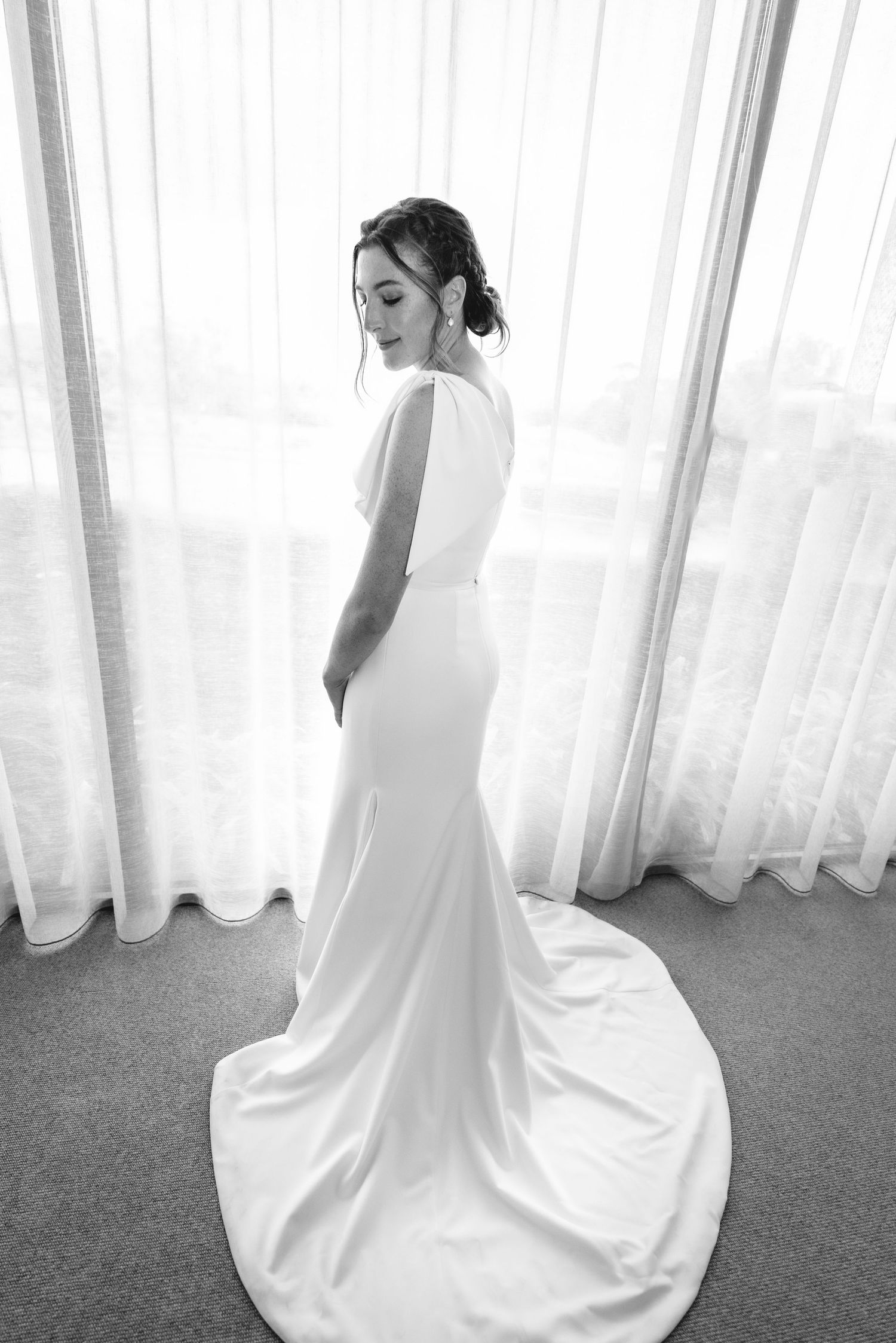 A series of four black and white photos showing a bride in a flowing white dress against sheer curtains.