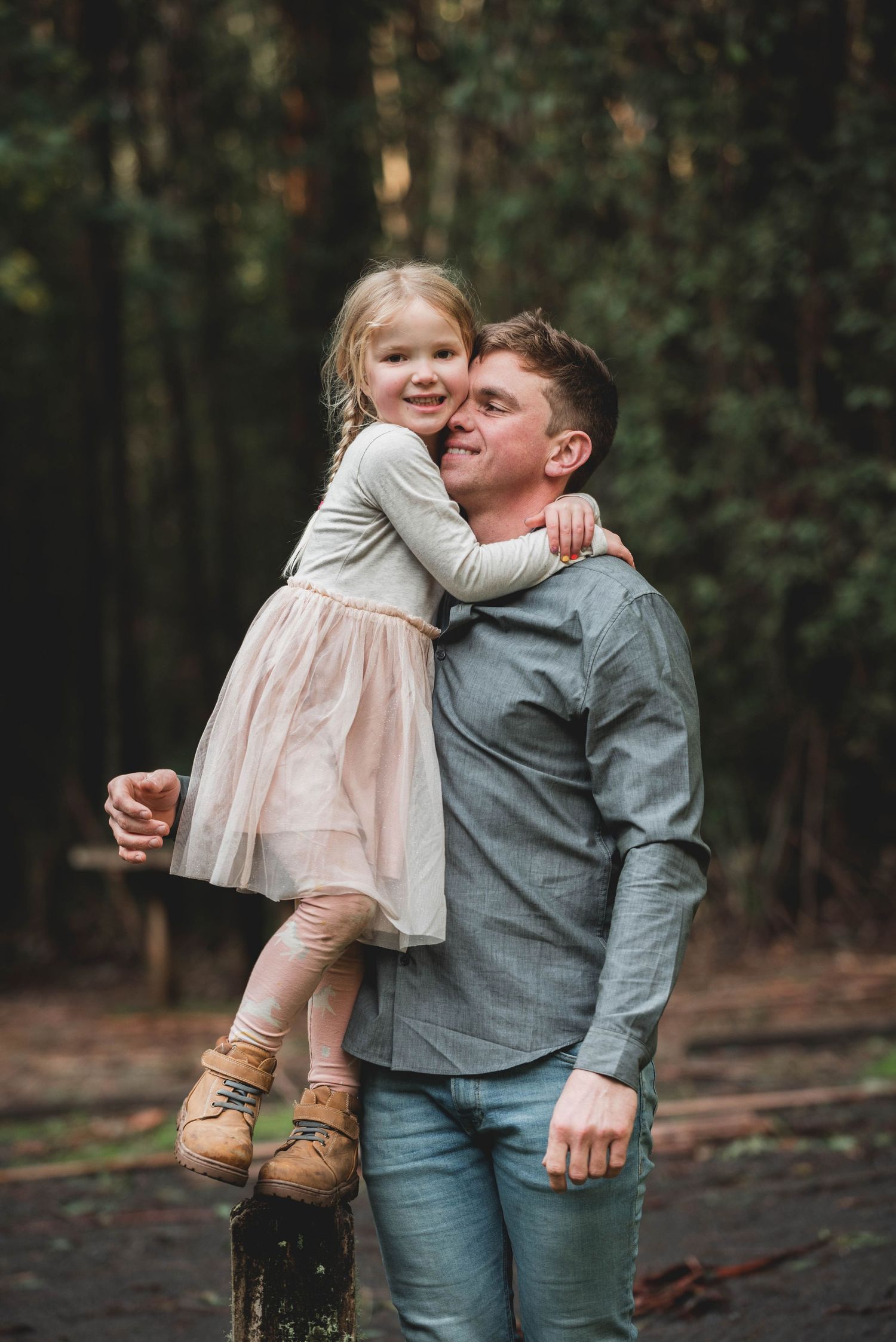 A tender moment captured in the woods as parent and child share a loving embrace while standing among trees.