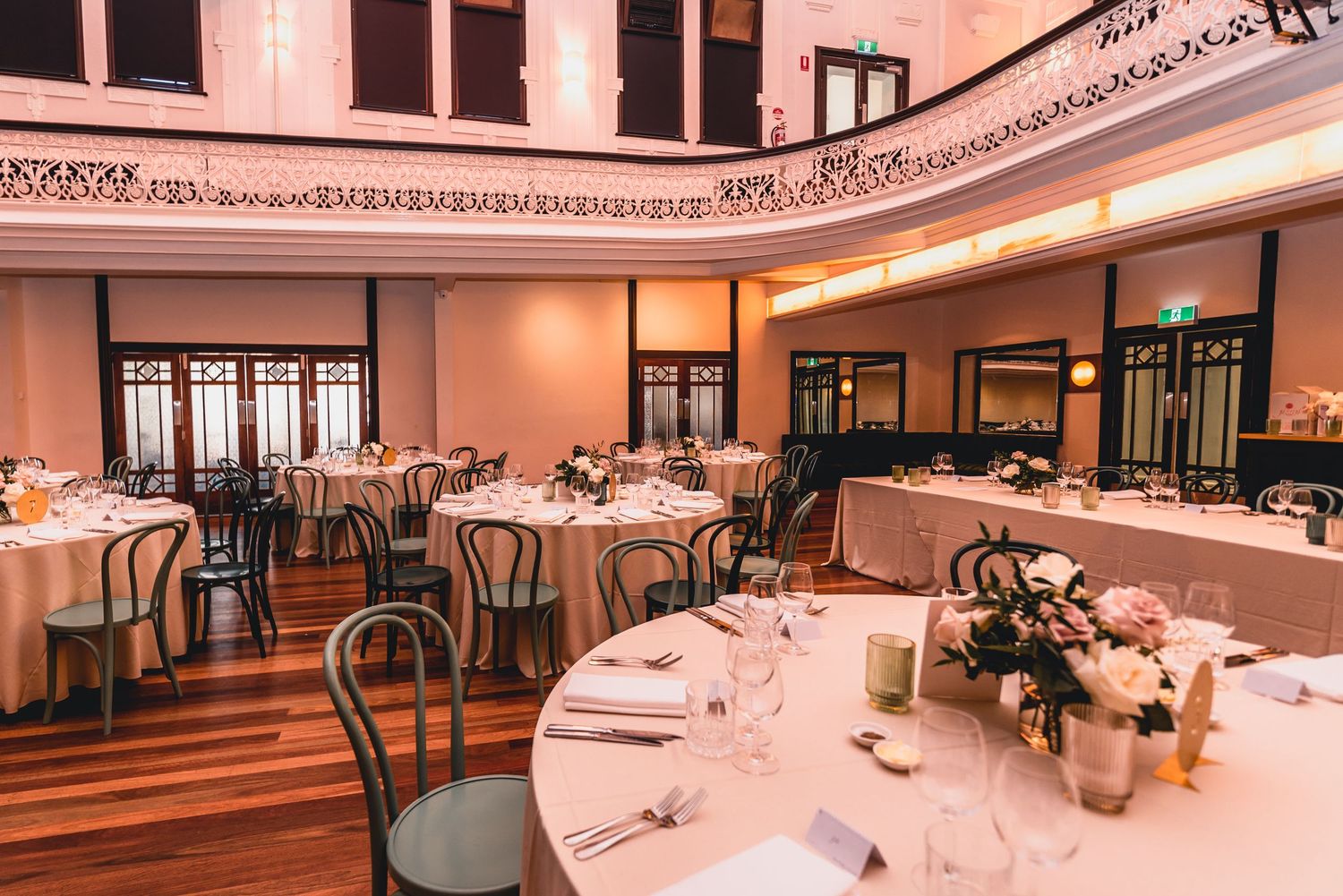 Elegant banquet hall interior with round tables, white tablecloths, and ornate architectural details in warm lighting.