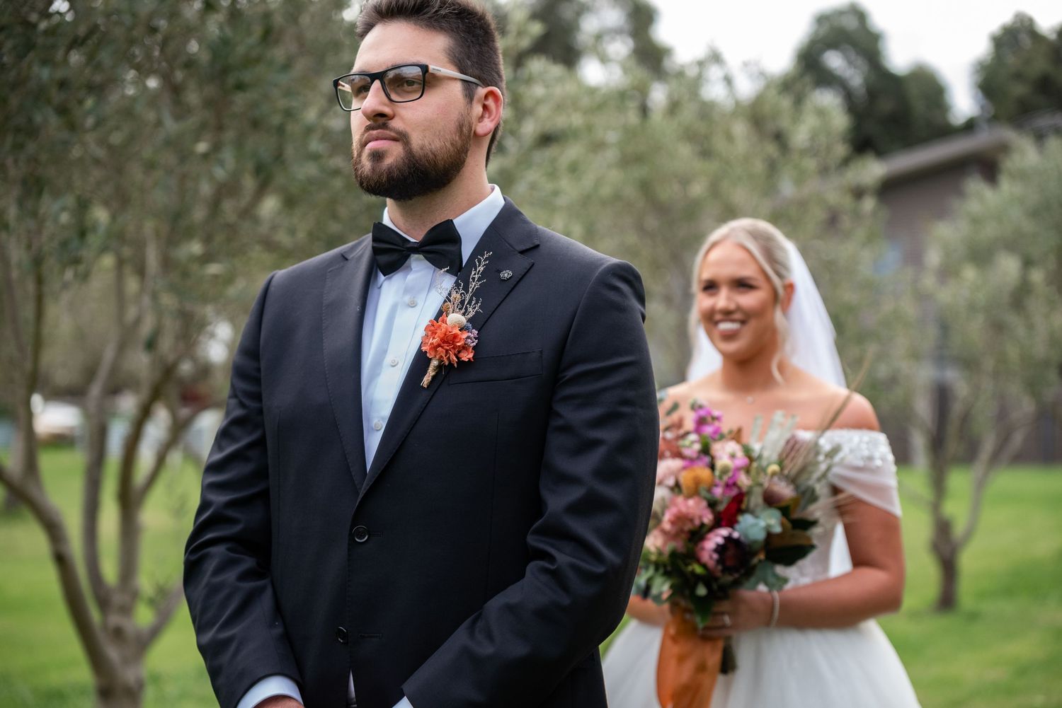 A couple shares a romantic moment during their wedding ceremony in a lush outdoor garden setting.