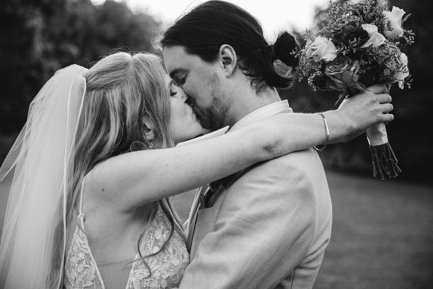 A romantic black and white sequence of newlyweds sharing intimate moments during their outdoor wedding.