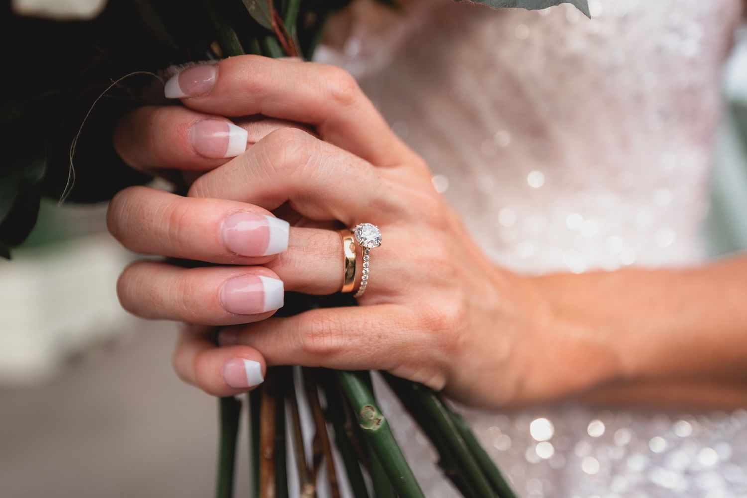 Close-up of hands with engagement rings exchanging vows during an intimate wedding ceremony.