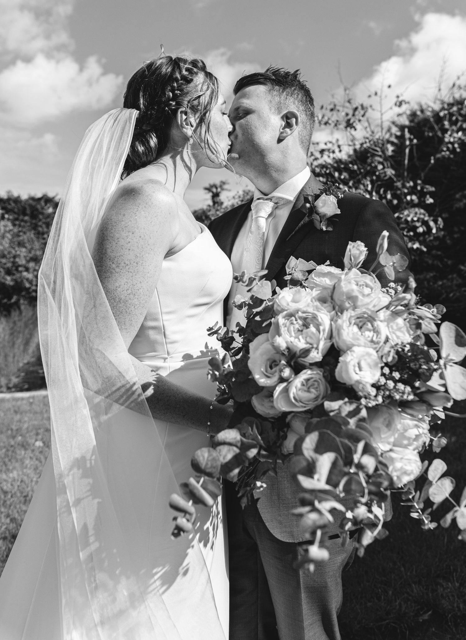 A romantic black and white wedding photo series showing tender moments between newlyweds with elegant white floral bouquets.