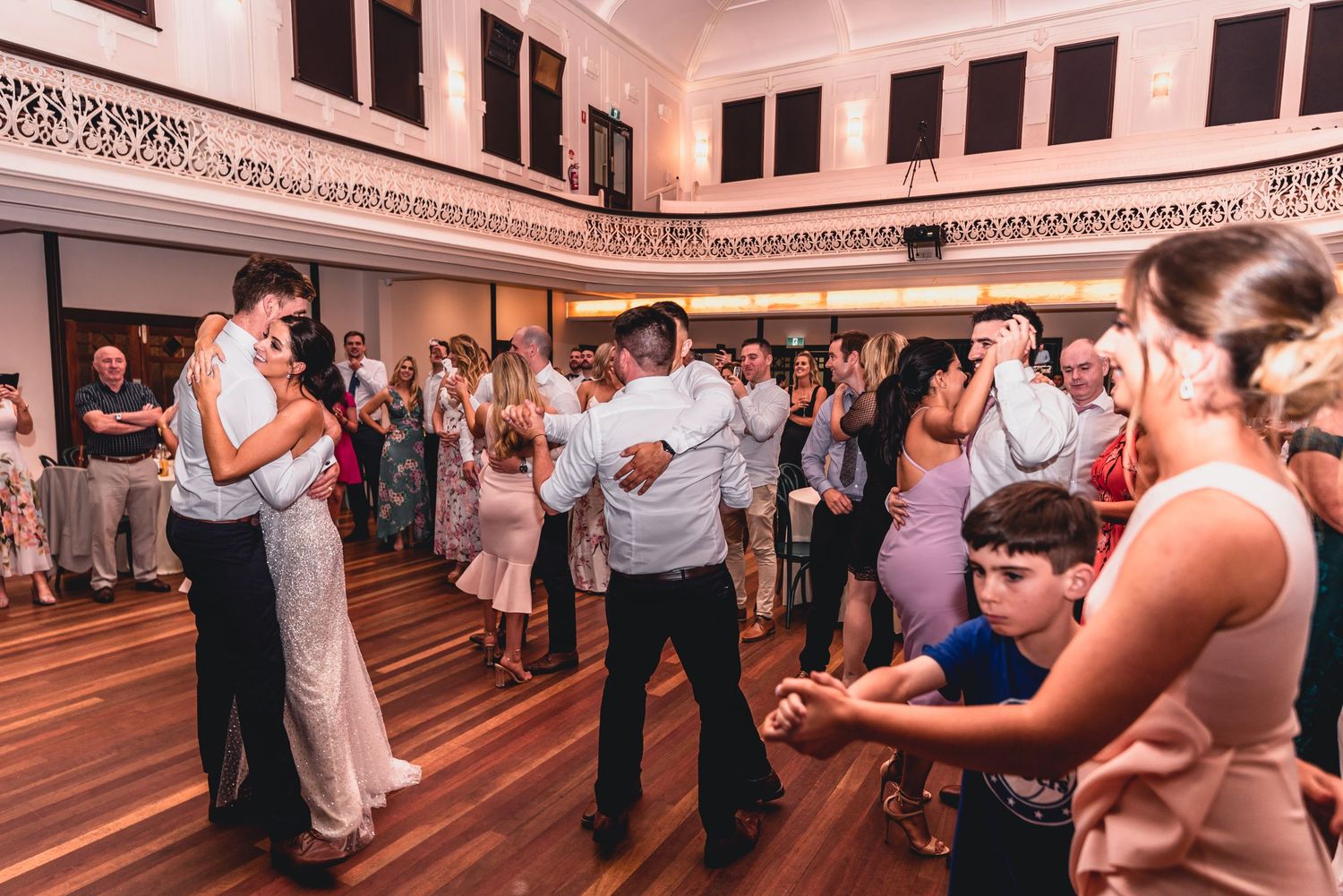 Couples dancing together at a social ballroom dance event in an elegant indoor venue.