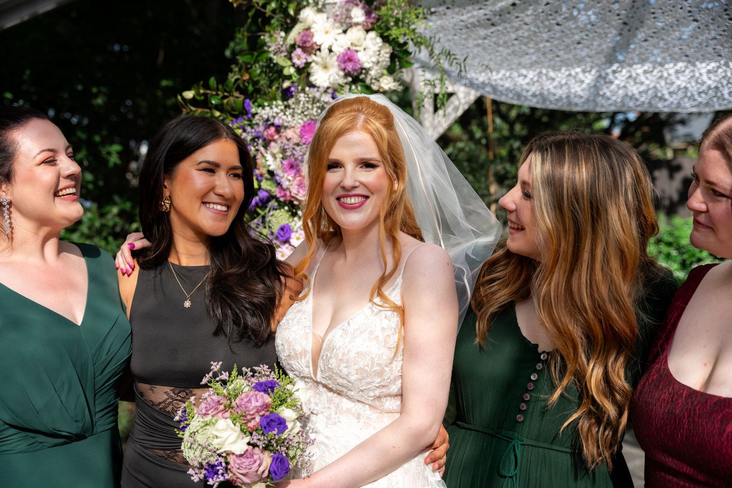 Wedding party gathered outdoors with colorful bouquets and formal attire.