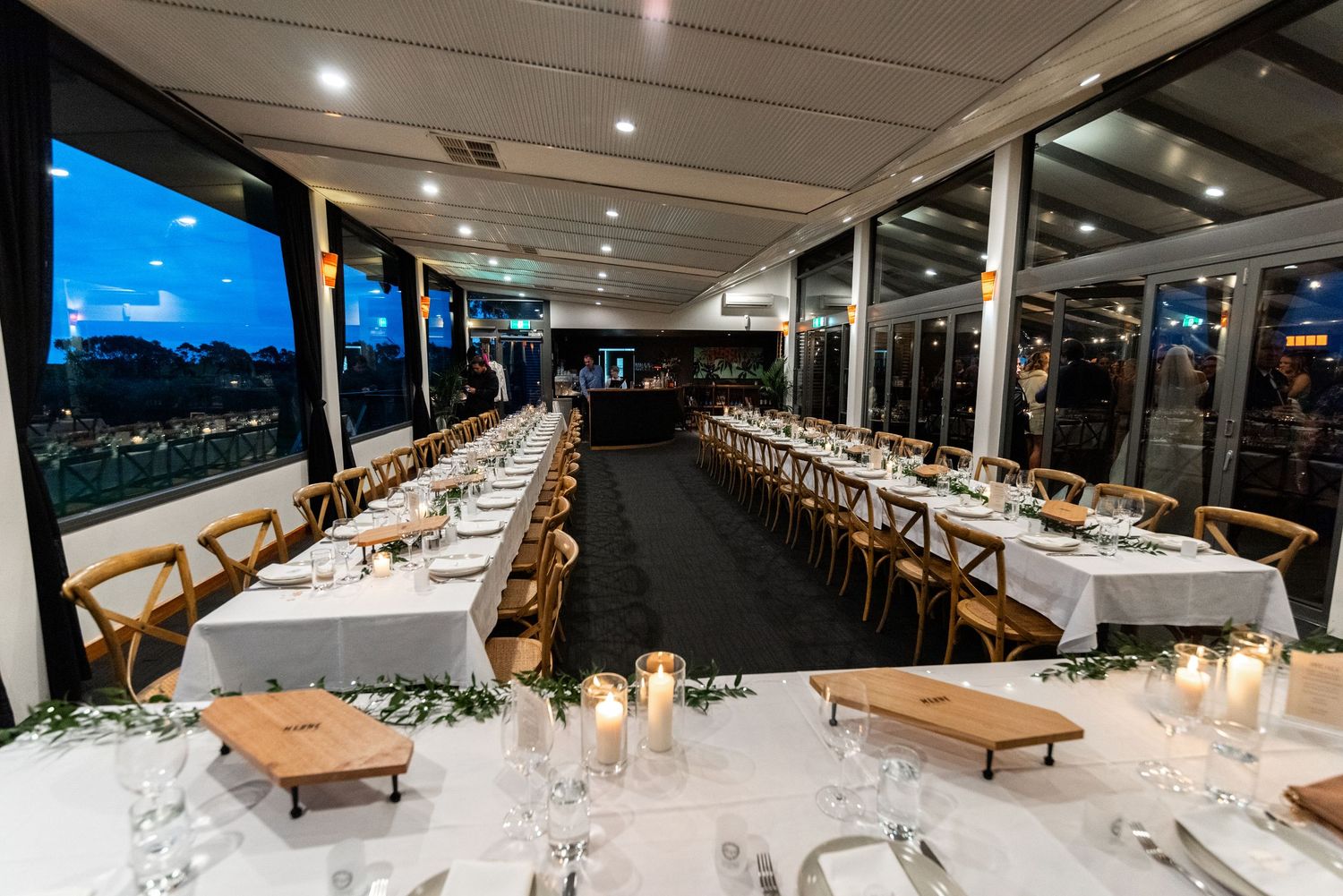 Modern wedding reception venue with long tables and ambient lighting creating an elegant atmosphere.
