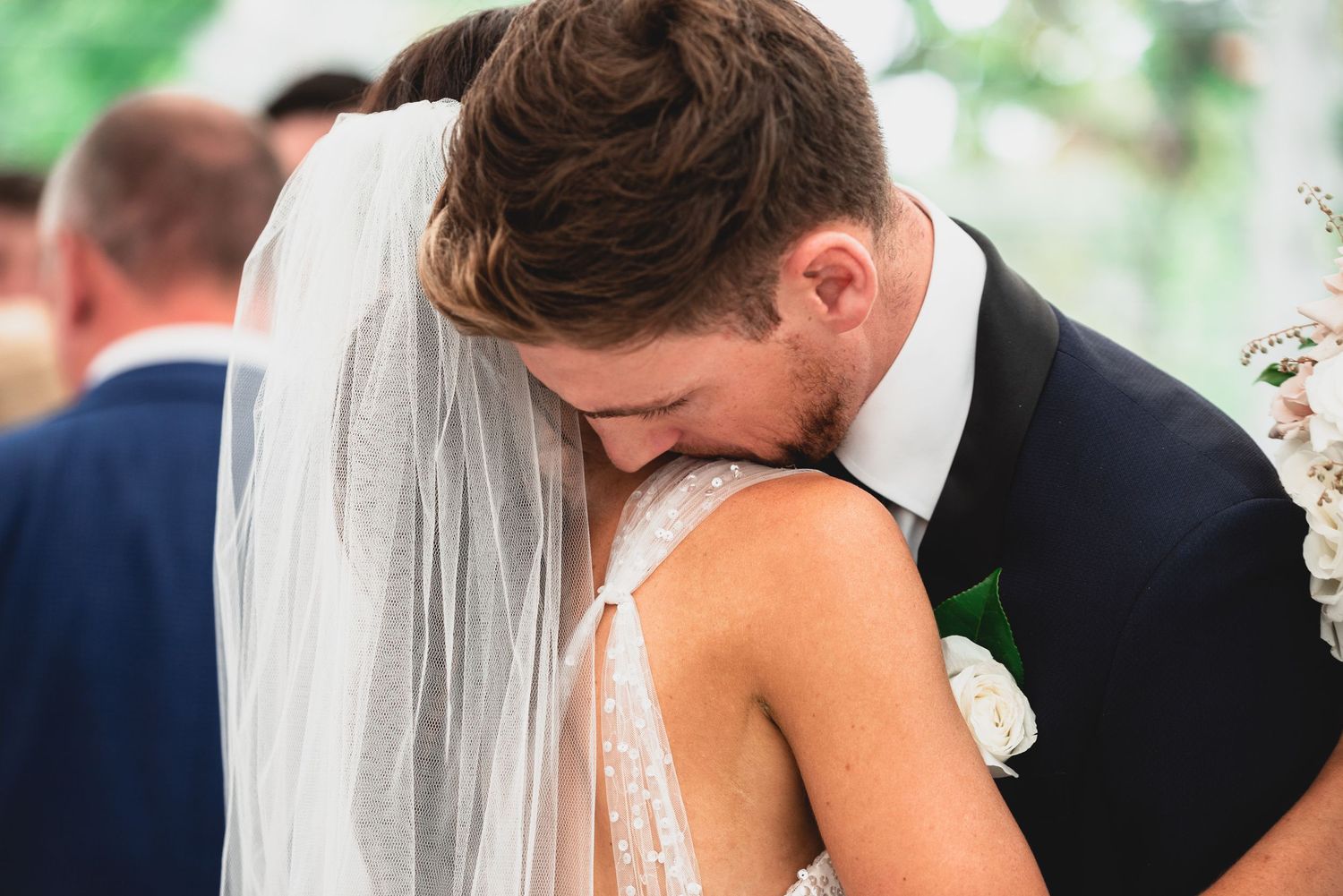 A tender moment between newlyweds as they embrace during their outdoor wedding ceremony.