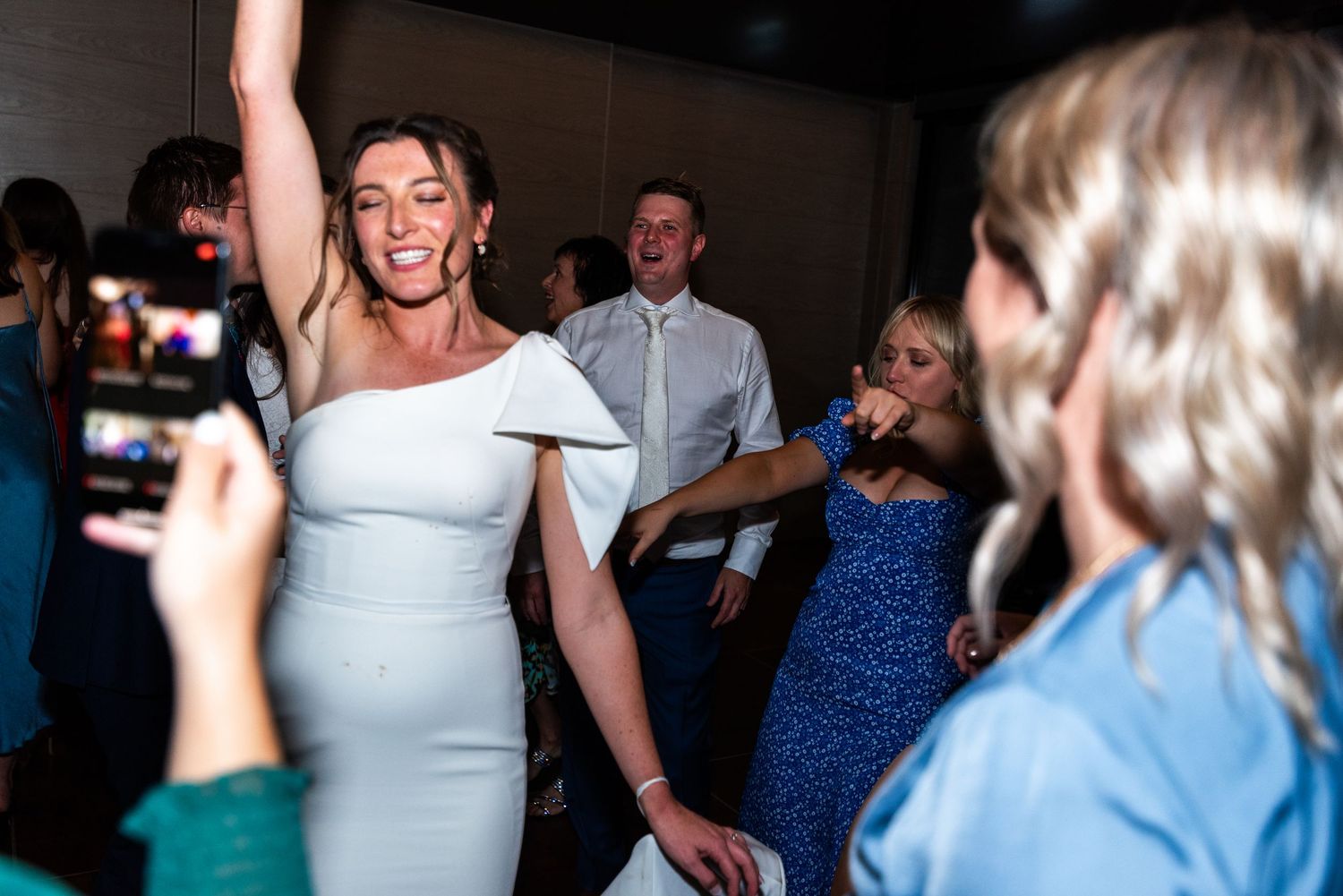 Wedding guests dance and celebrate together on a crowded dance floor at an evening reception.