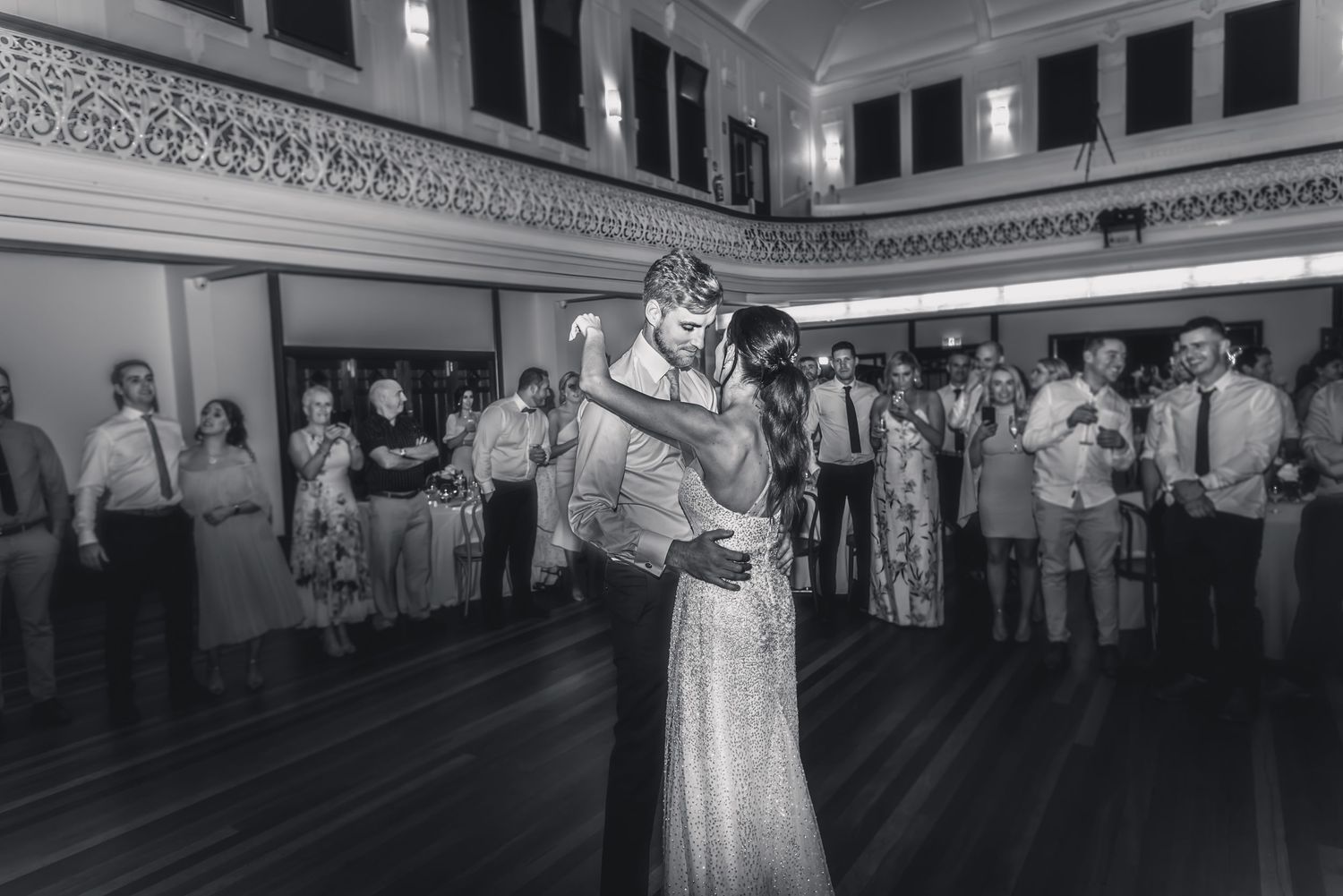 A vintage black and white photograph shows couples dancing together in a large ballroom setting.
