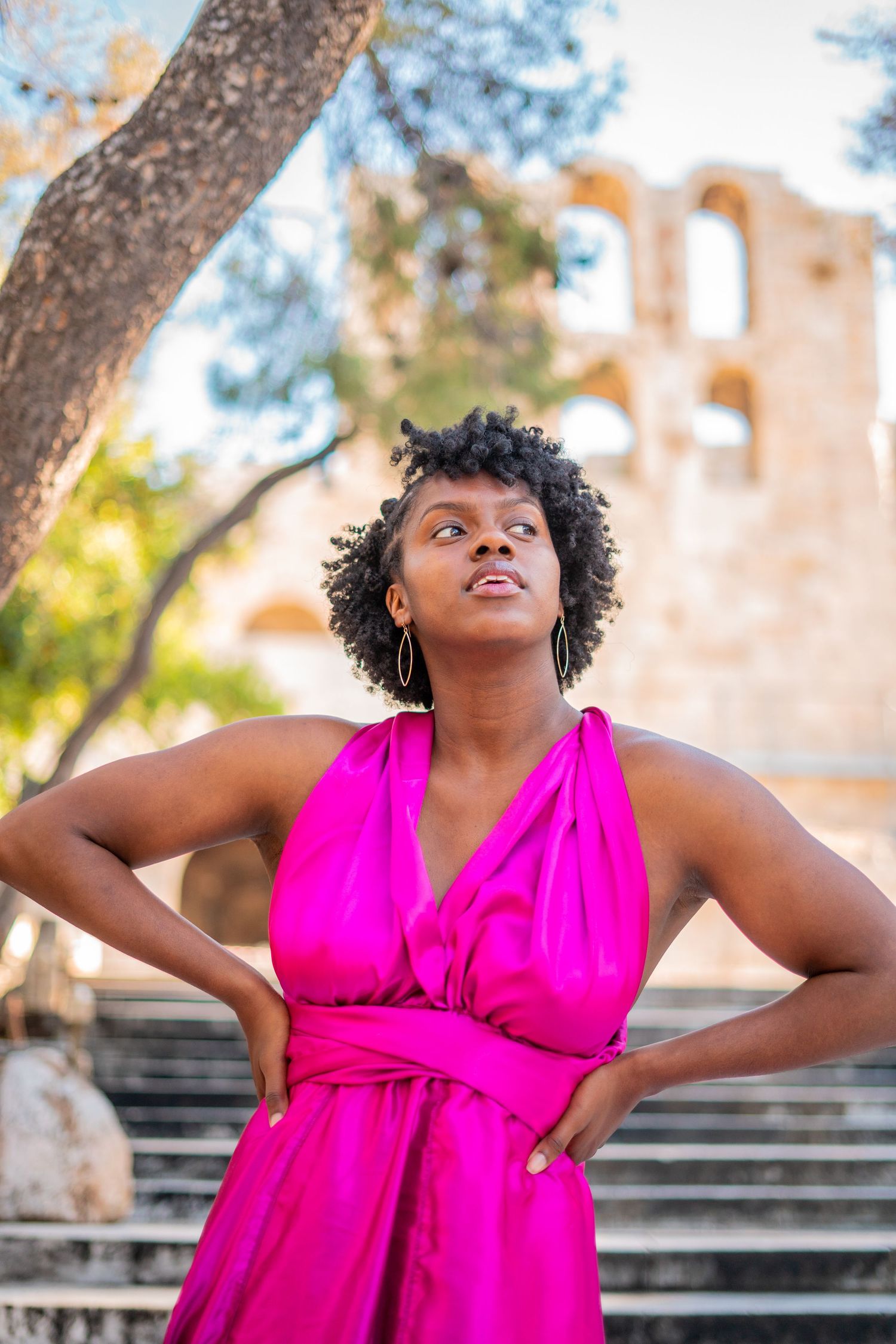 Vibrant pink wrap dress styled against ancient stone steps and architecture.