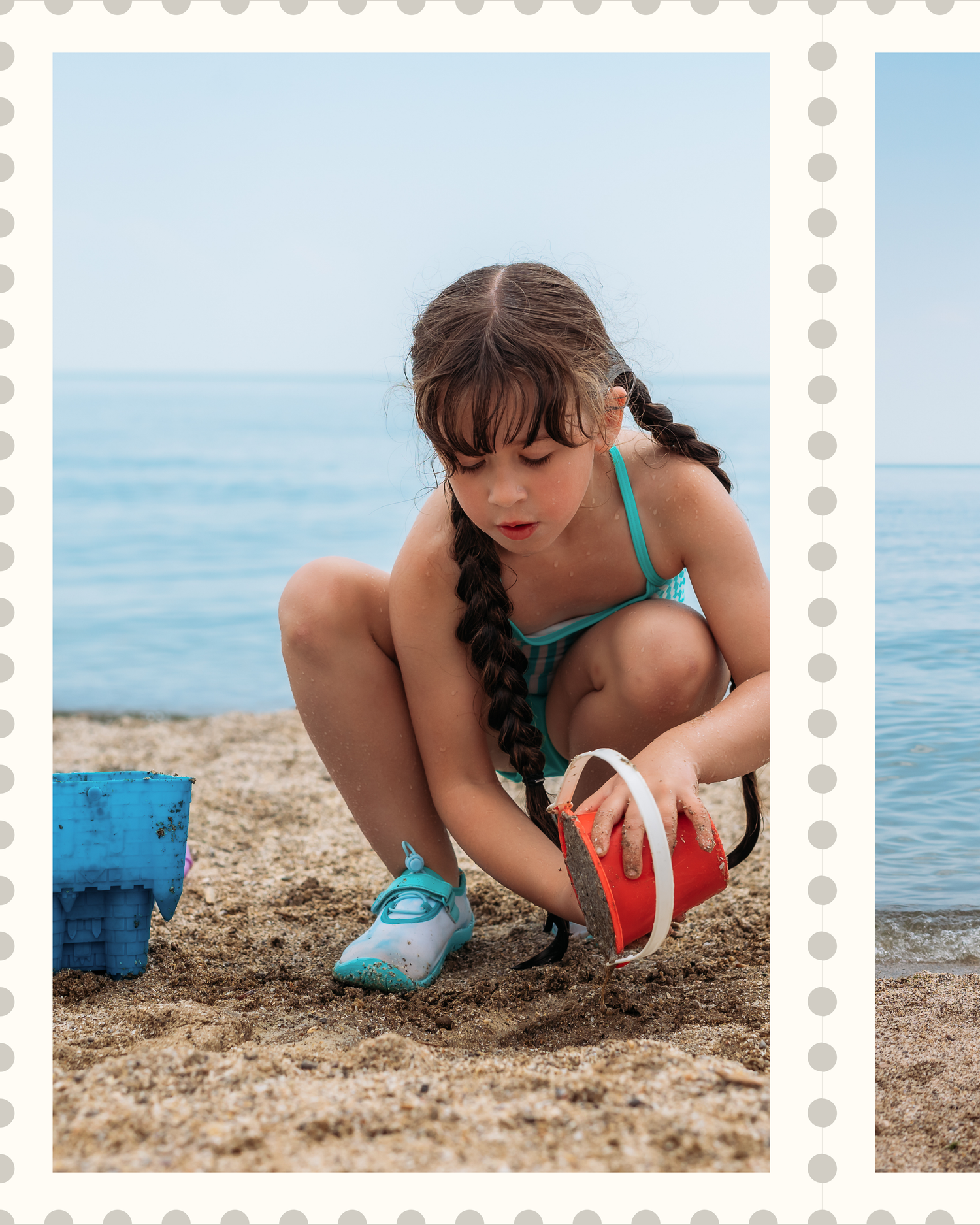 Someone in braided hair and turquoise swimwear crouches on a sandy beach to collect or examine something on the ground.