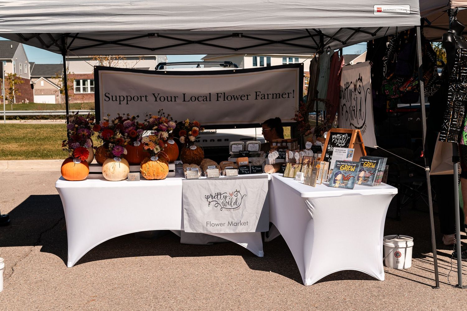 Support Your Local Flower Farmer vendor booth with pumpkins, dried flowers, and jars at an outdoor market.