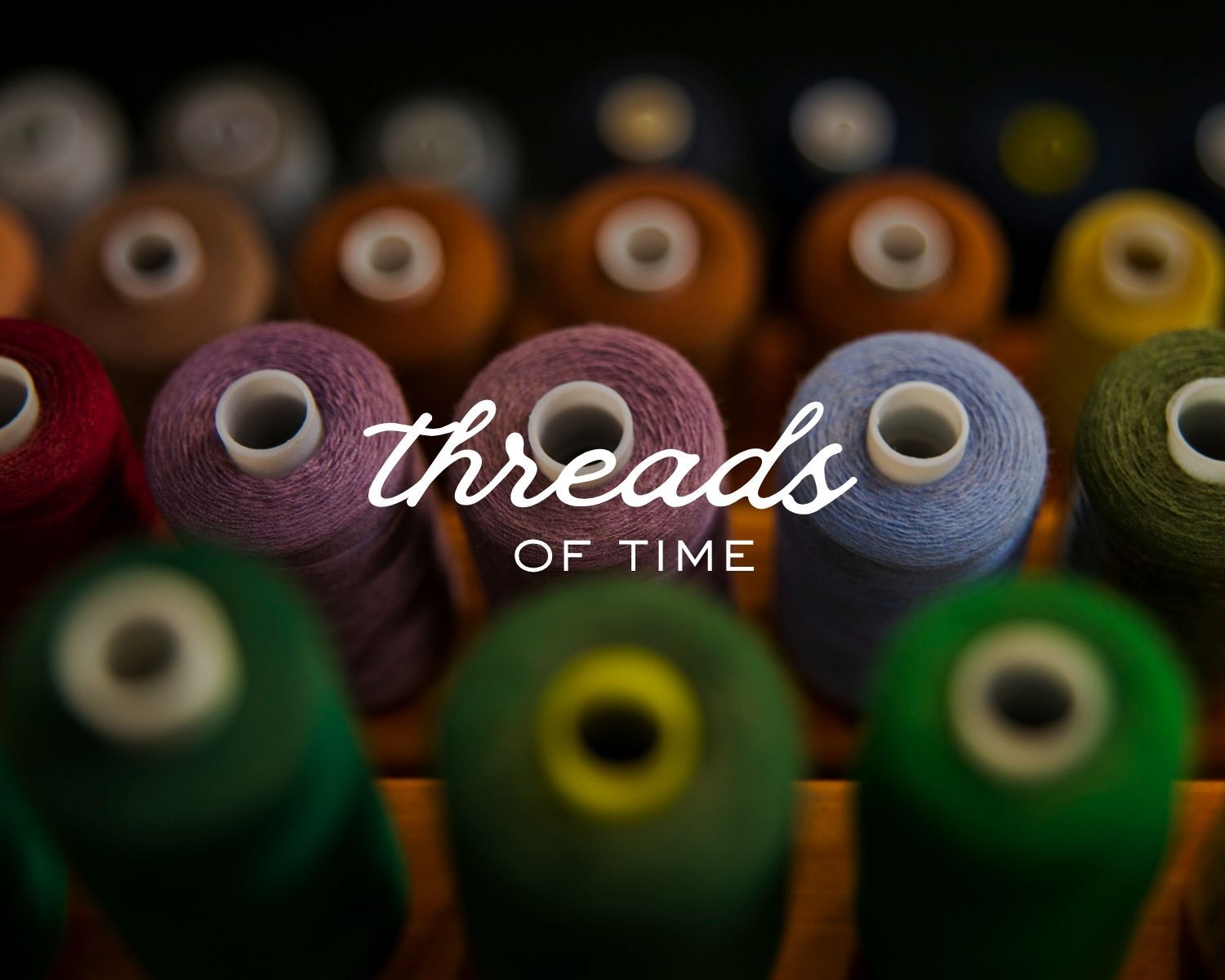 Colorful thread spools in red, purple, green, and orange arranged in rows with Threads of Time text overlay.