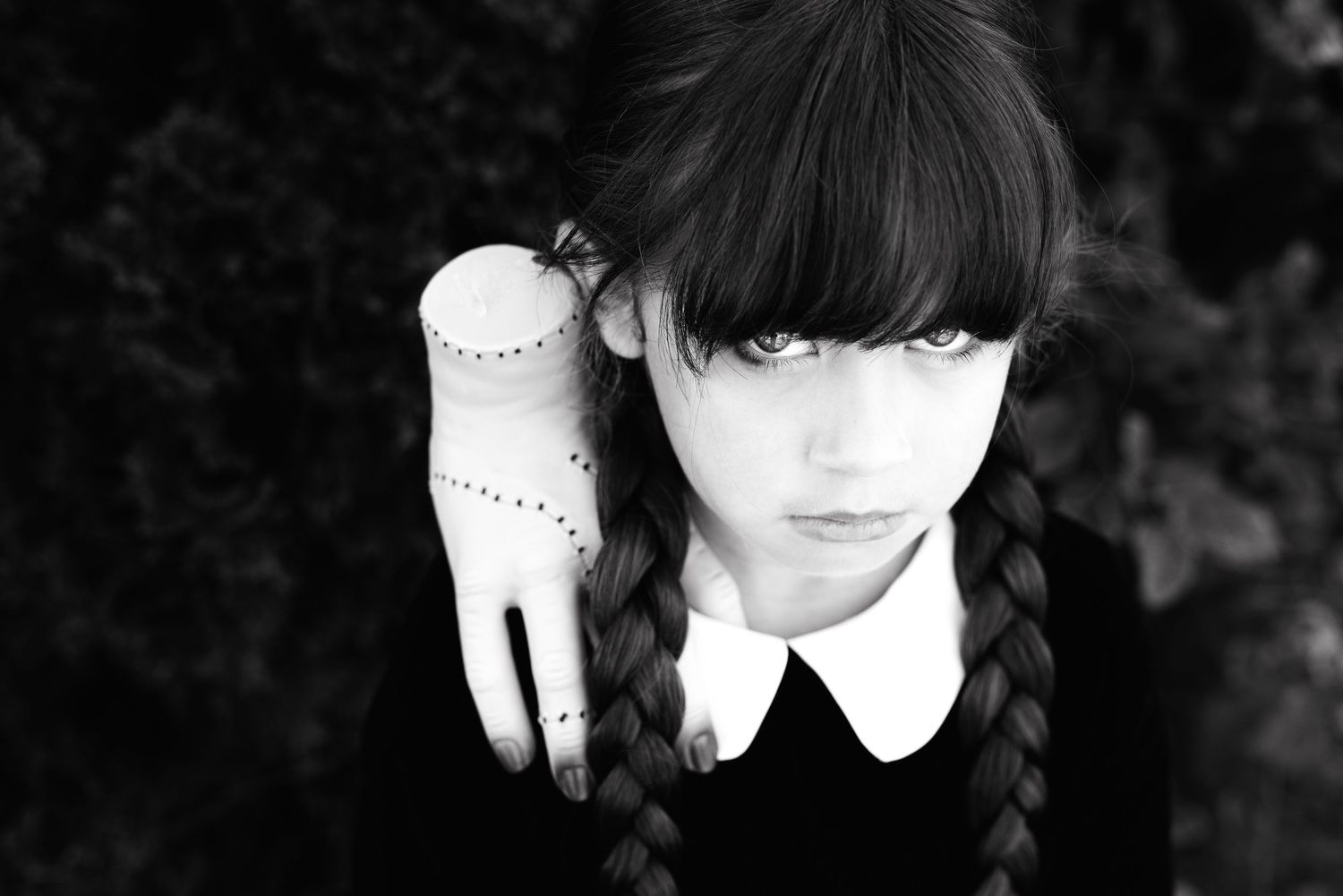 Artistic black and white portrait featuring dark braided hair and a white collar against a moody background.