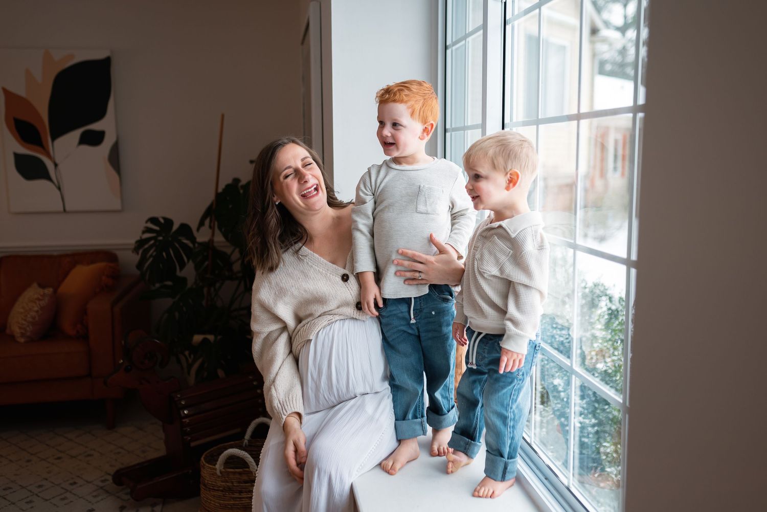 Playful family moment by large window with modern home decor.