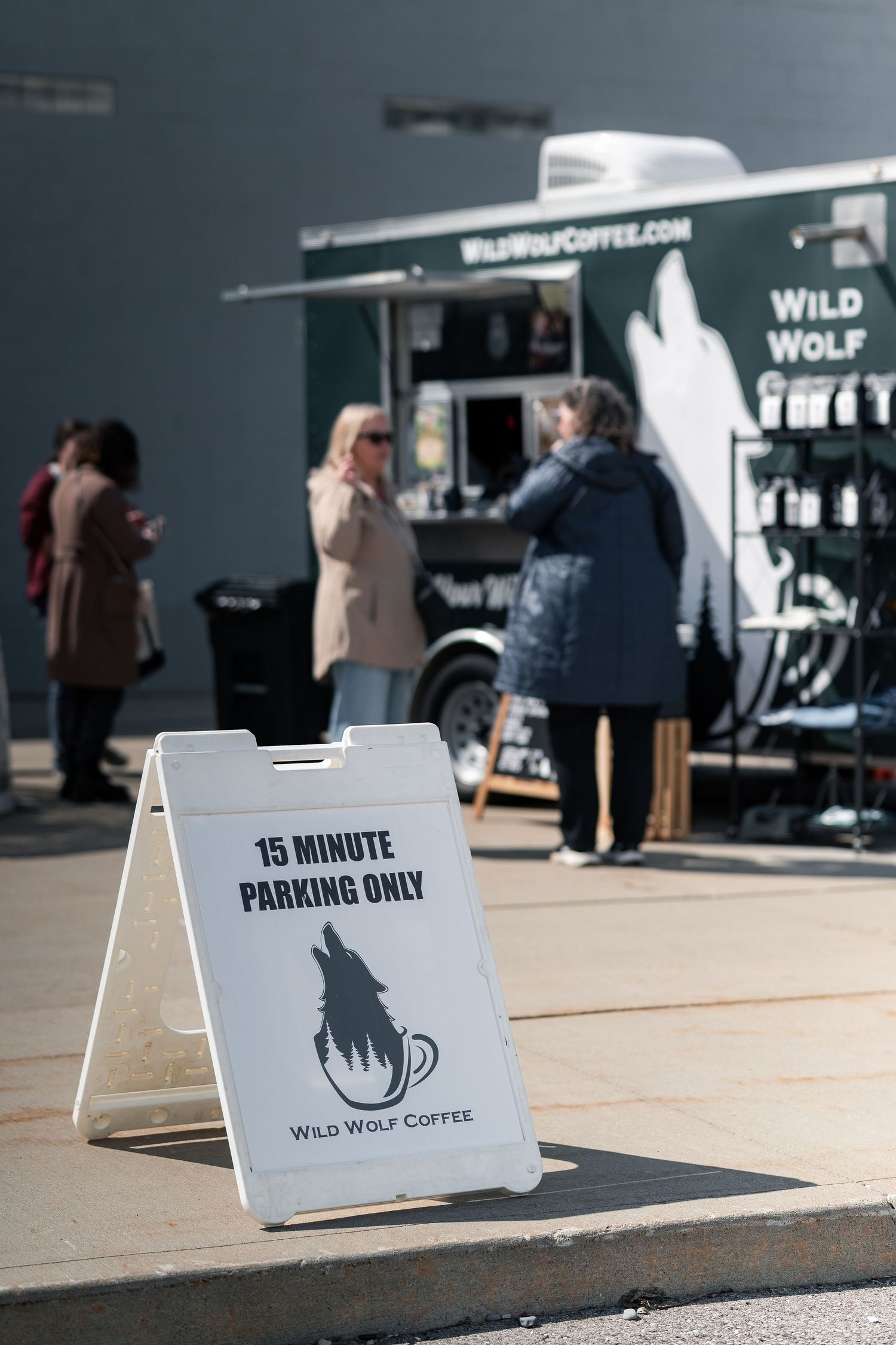 Wild Wolf Coffee food truck with customers ordering outside, featuring a 15-minute parking only sign in foreground.