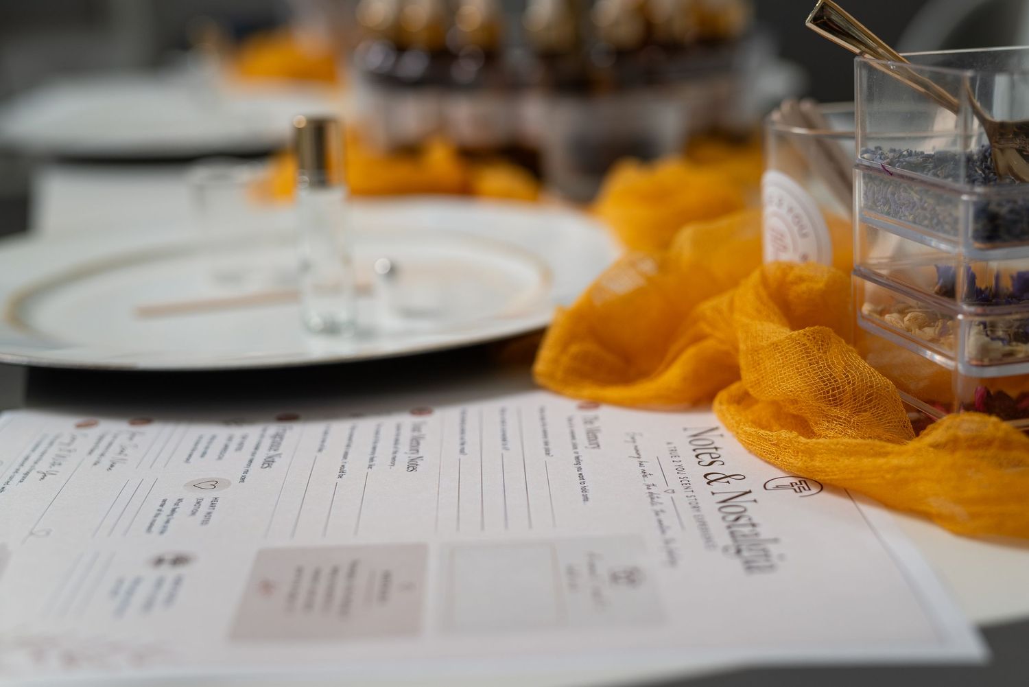 Elegant event table setup with golden yellow fabric, white plates, menus, and glass decor for a formal occasion.