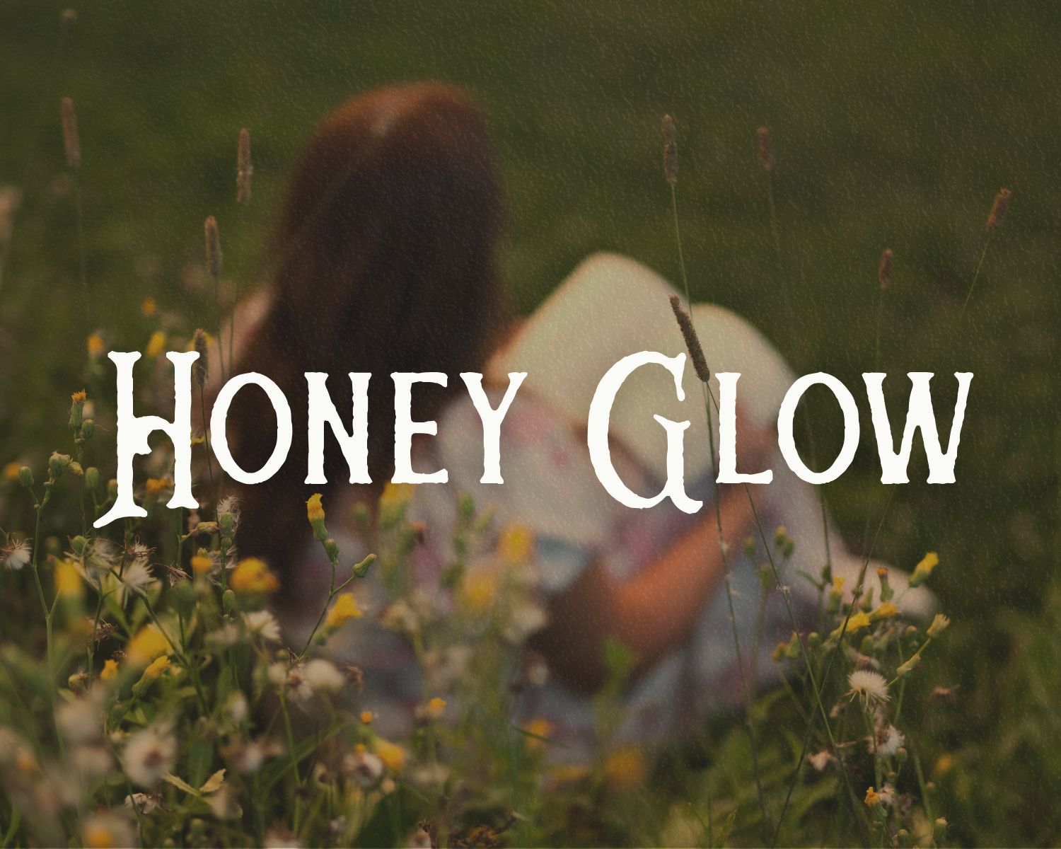 A woman sits in a wildflower meadow with text overlay reading Honey Glow in vintage serif font.