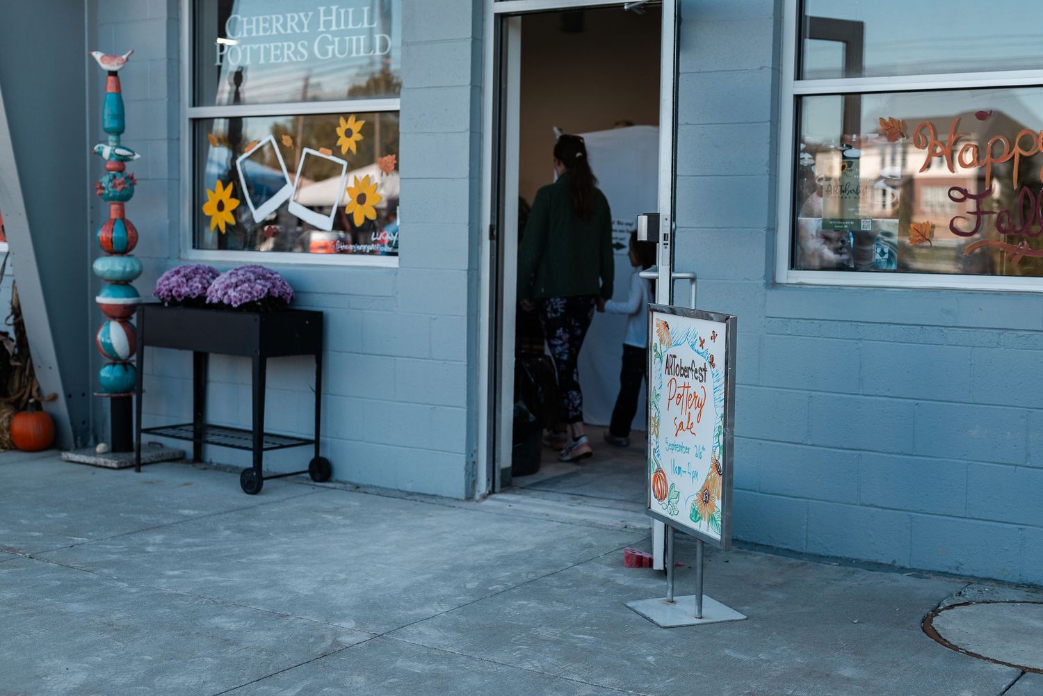 Cherry Hill Potters Guild storefront entrance with colorful ceramic art displays and an event sign outside.