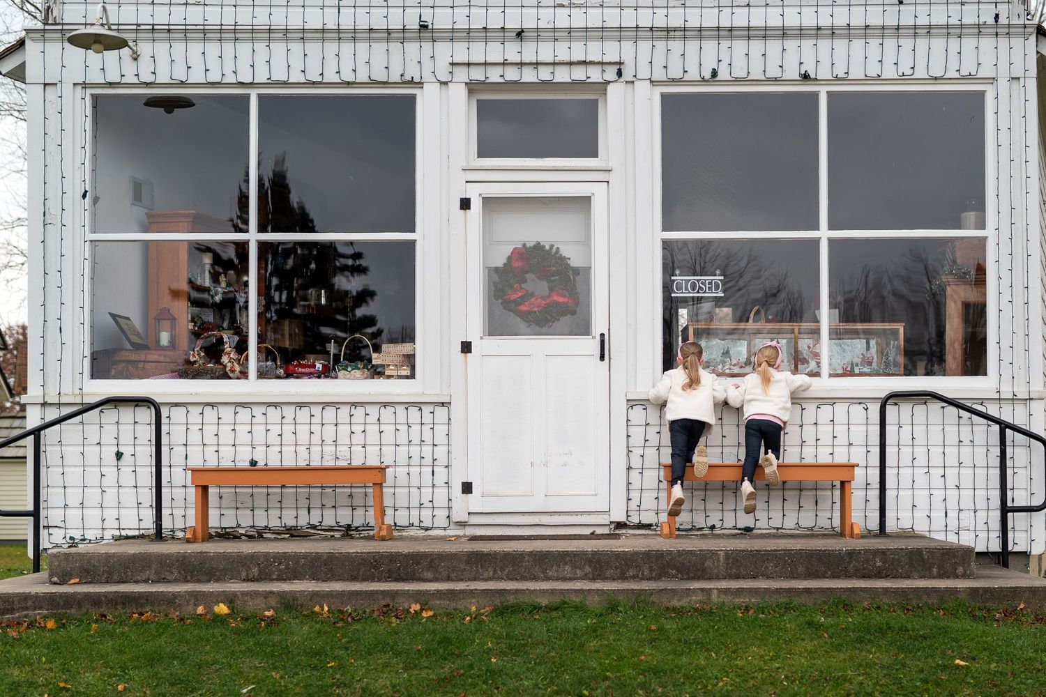 A white storefront with large windows showcasing Christmas decorations and a festive holiday display.
