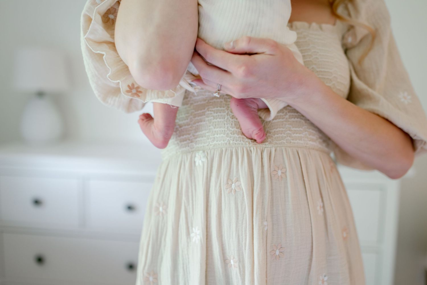 Detailed view of a cream colored vintage-style dress with delicate lace trim and gathered waist details.