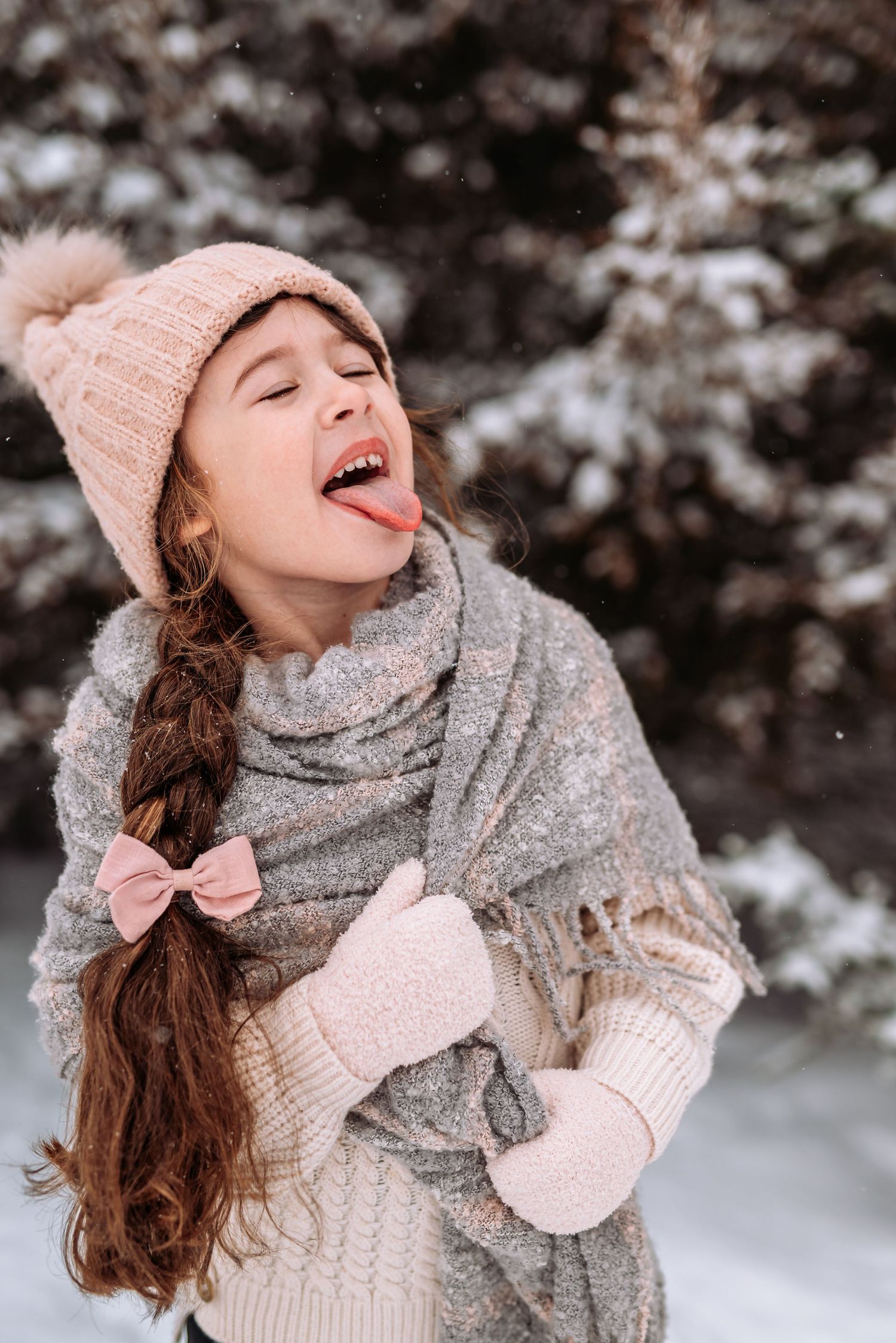 A joyful winter scene with a person wearing a cozy gray scarf, pink hat, and mittens enjoying the snowy outdoors.