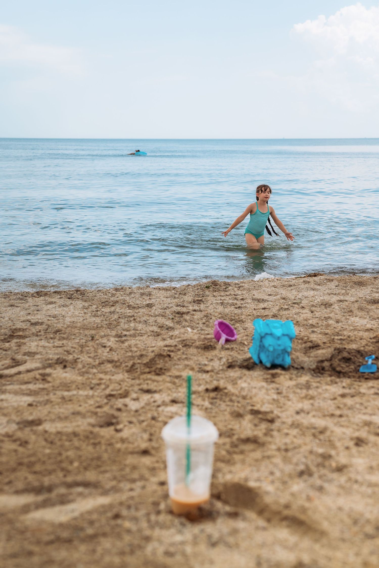 A collection of beach scenes featuring swimmers in the ocean, sandy shoreline, beachgoers, and a cold drink in the foreground.