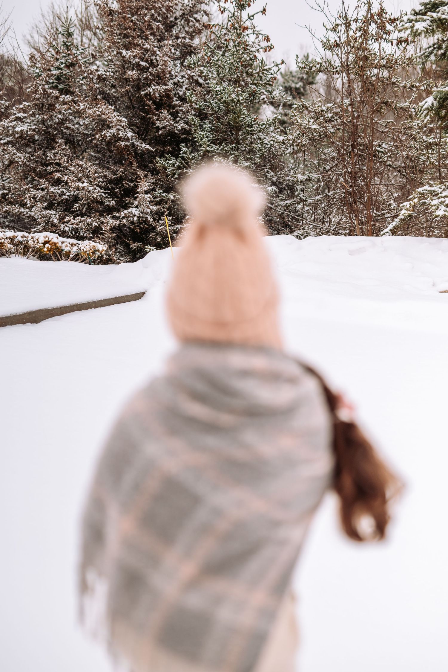 A sequence of motion blur photos showing someone spinning in a snowy winter landscape with evergreen trees.