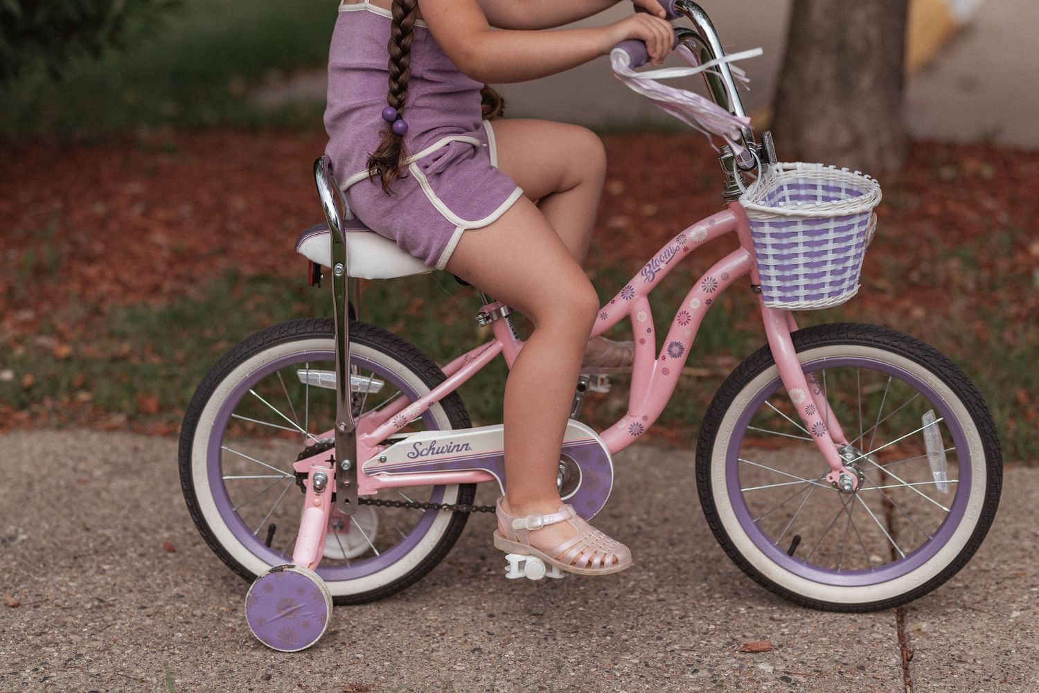 Close-up shots of someone wearing lavender shoes mounting a pink and white bicycle in different positions.