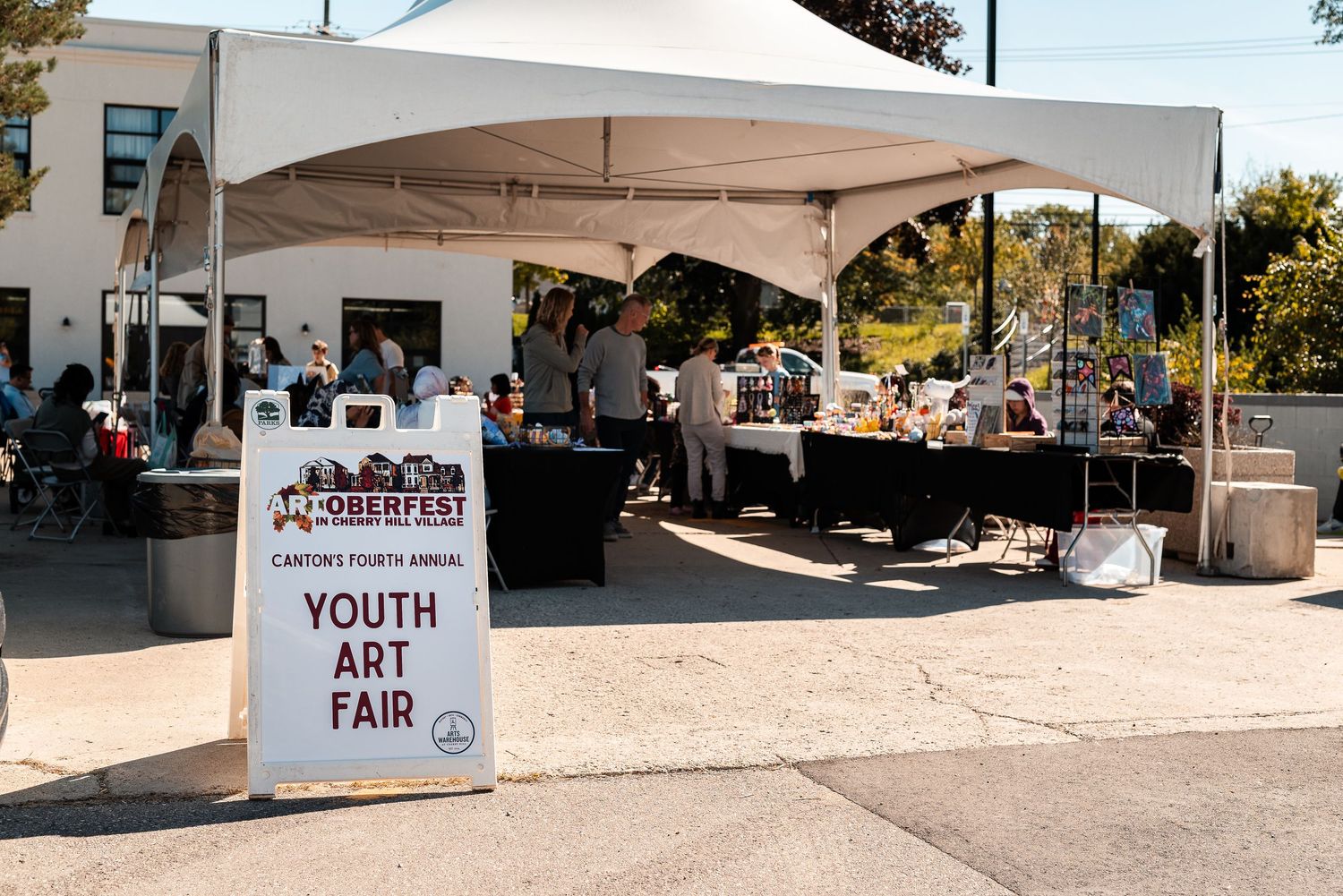 Outdoor youth art fair tent display at Octoberfest event on a sunny day.
