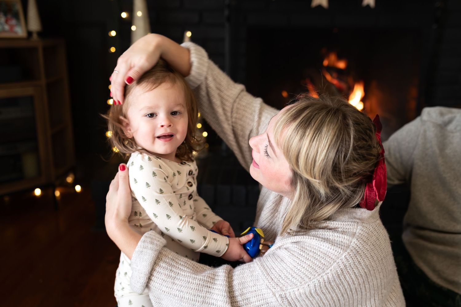 Sweet moment shared in front of cozy fireplace with twinkling holiday lights.