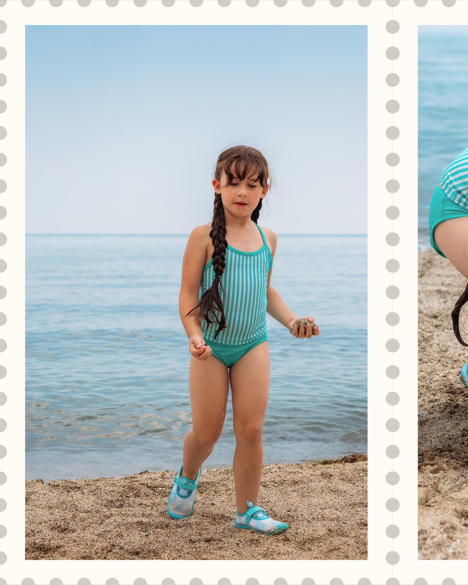 A young beachgoer in a turquoise striped swimsuit and blue shoes stands at the edge of calm ocean waters.