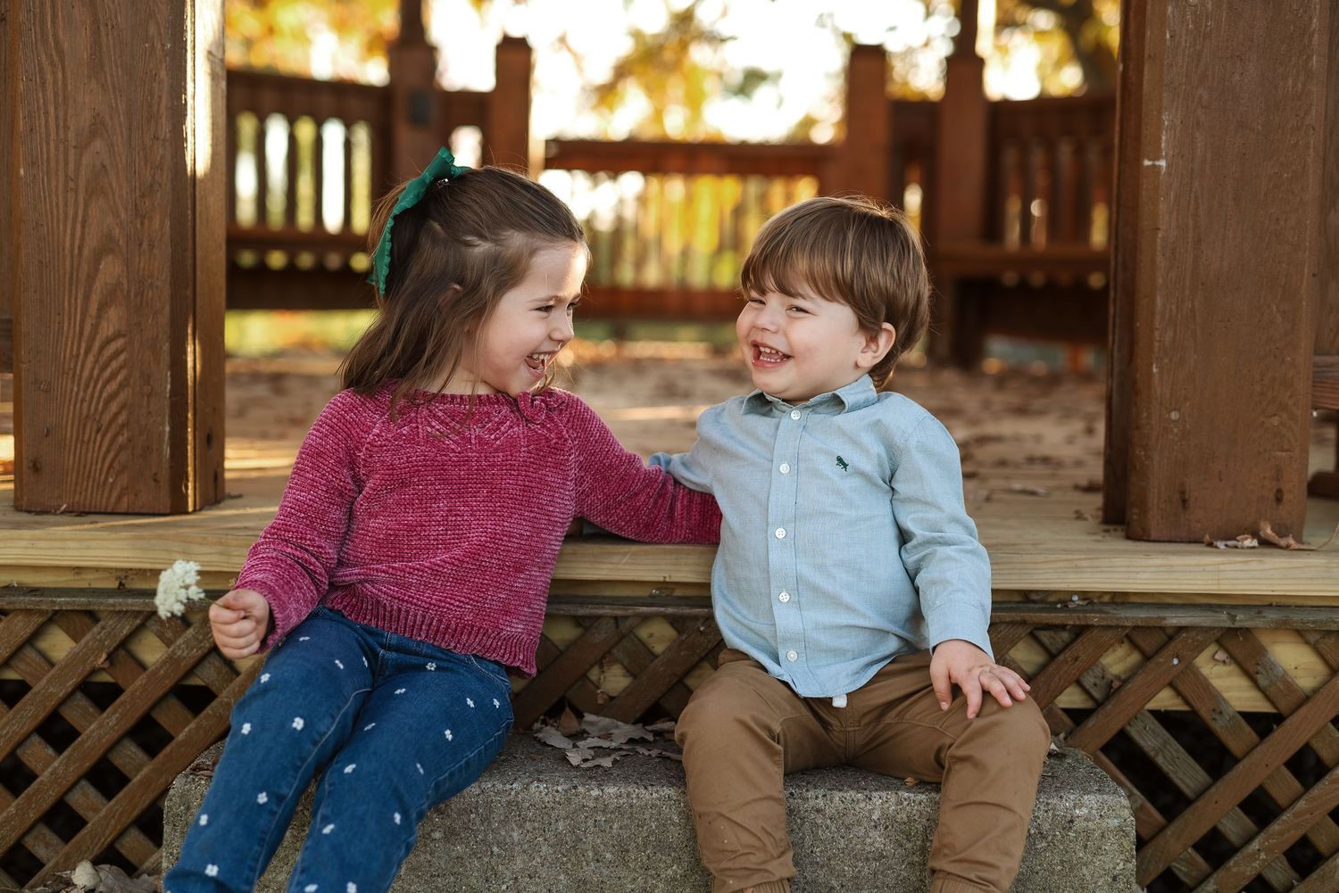 Joyful play session captured in warm sunlight through wooden lattice panels at a park.
