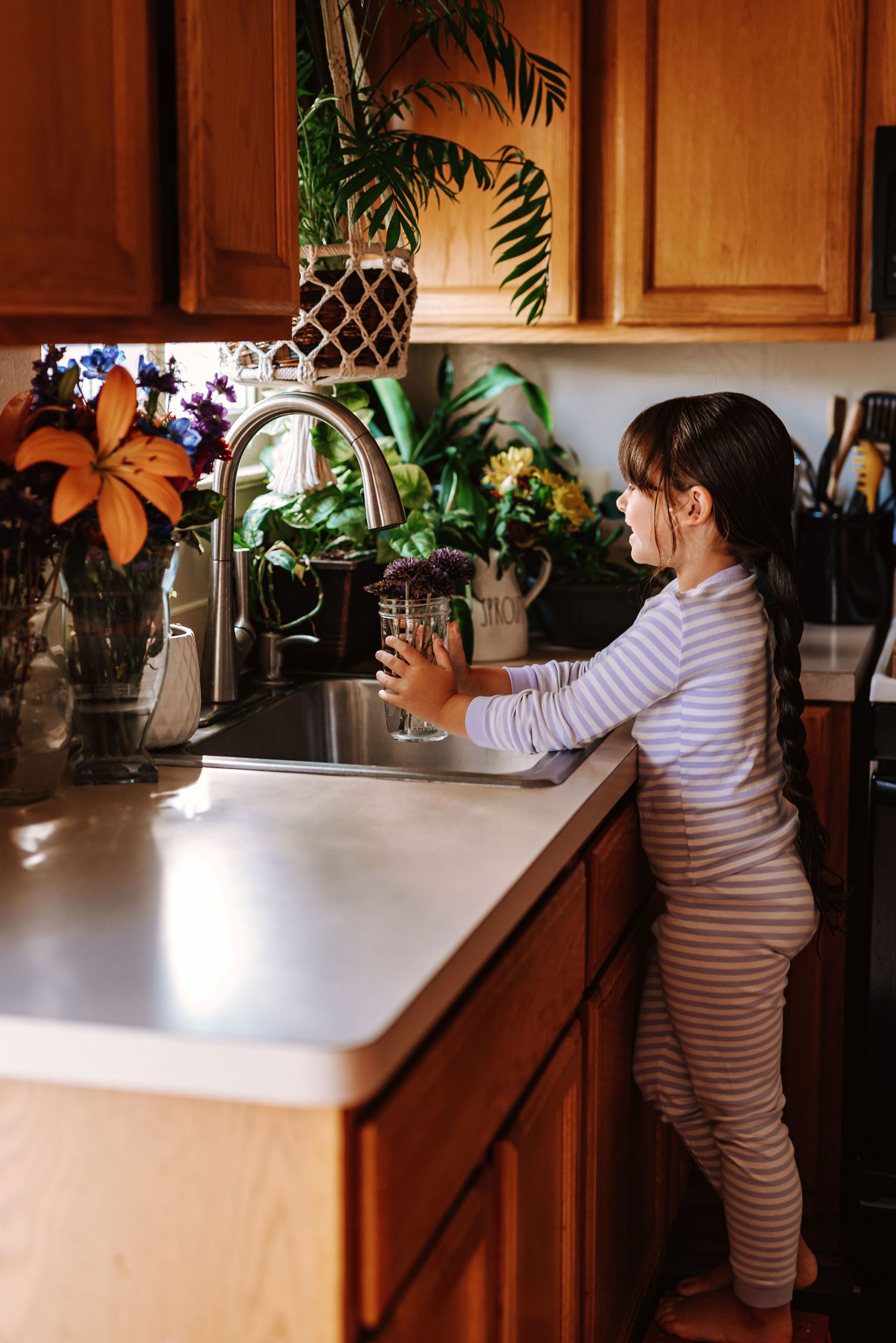 A person in striped clothing reaches across a kitchen counter with houseplants visible in the background.