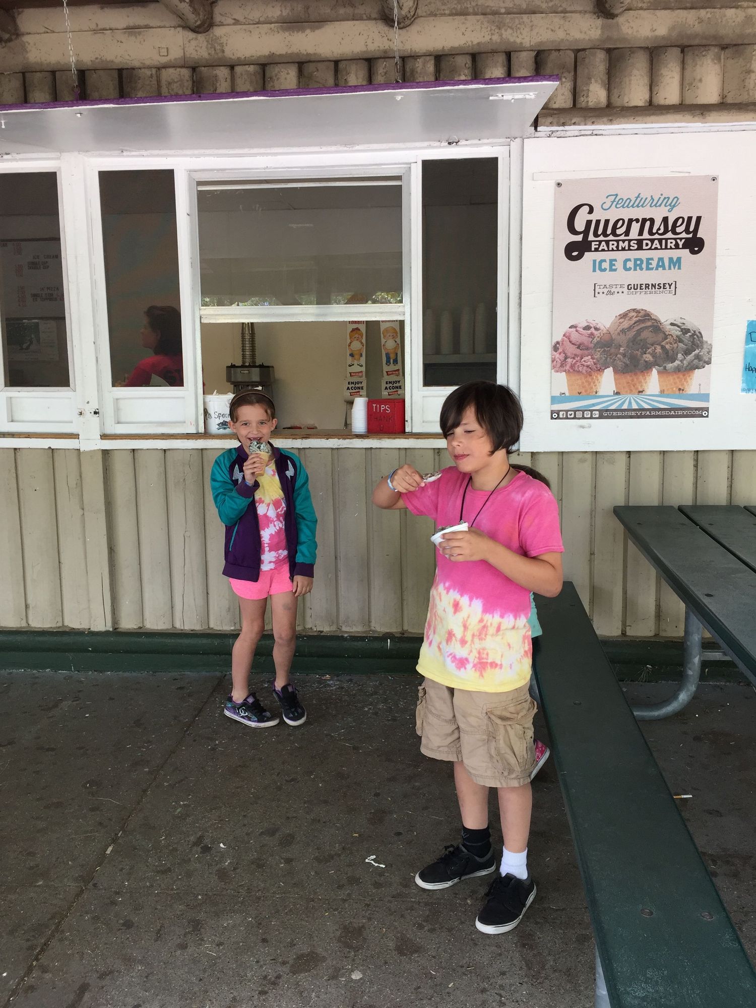 Two children enjoying Guernsey Farms Dairy ice cream outside a concession stand window.