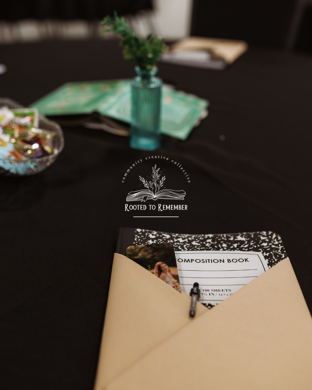 Rooted to Remember composition book in kraft envelope on black tablecloth at community event.