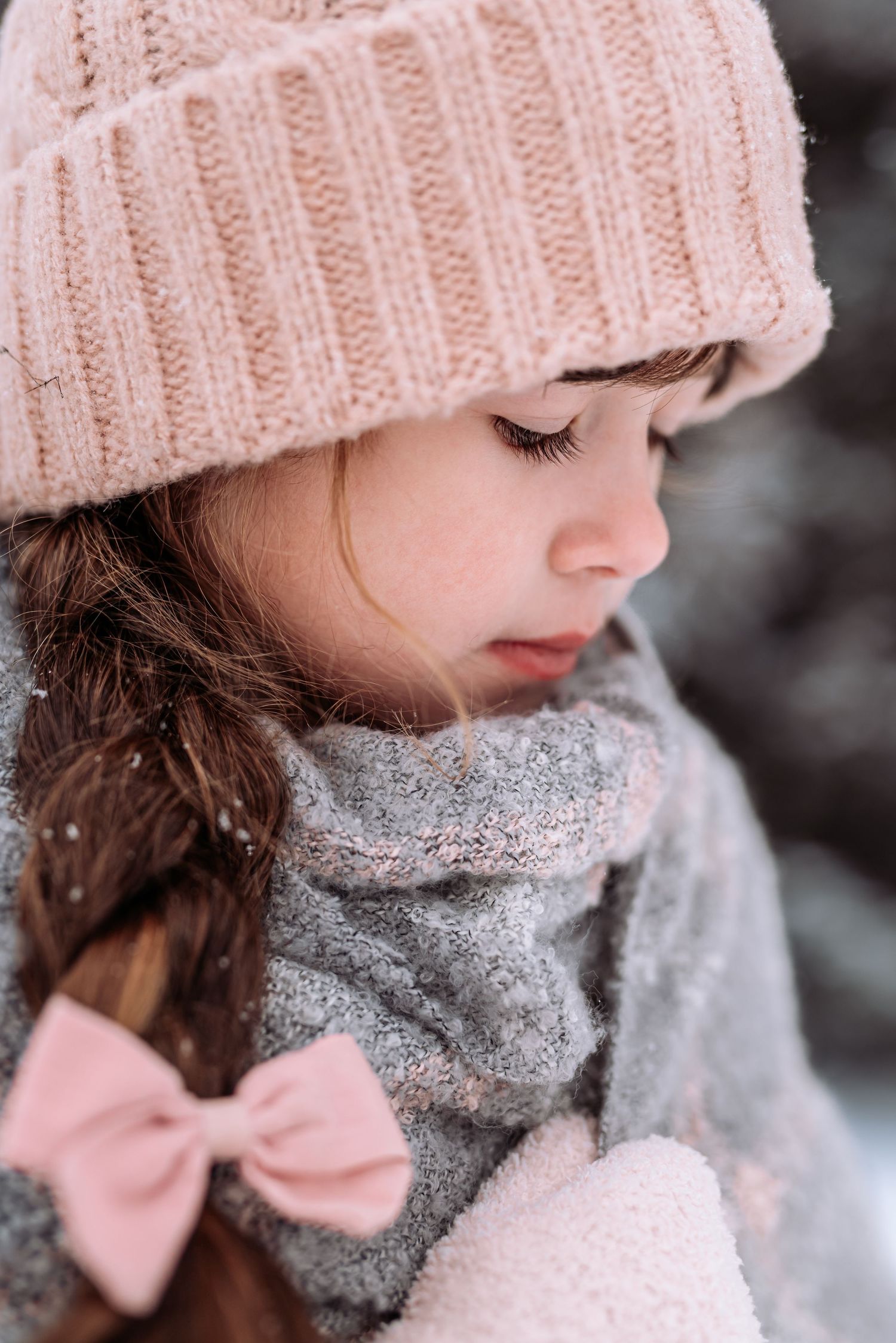 Close up winter portrait with pink knit beanie, gray scarf and soft pink bow details.