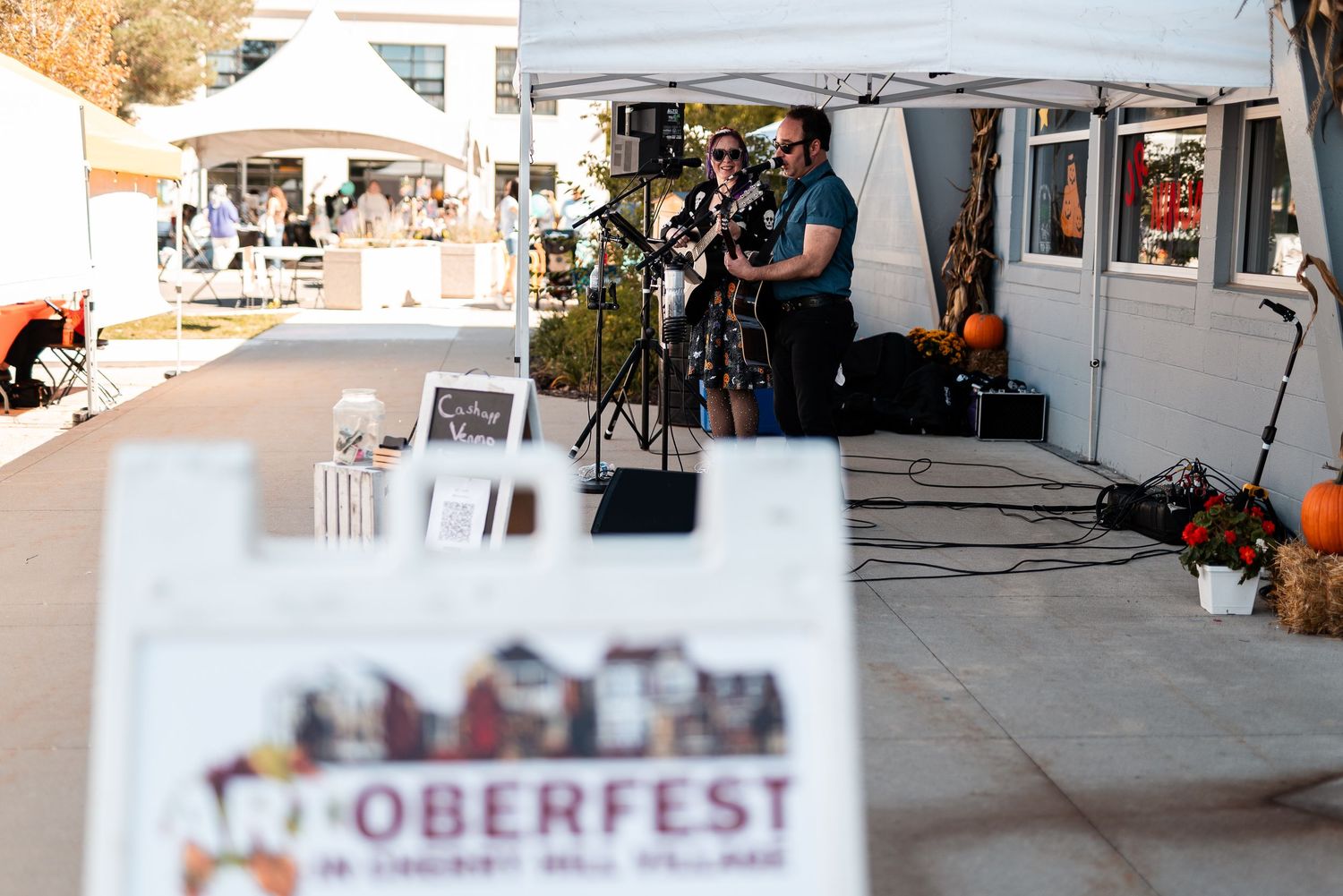 Two musicians performing on stage at Artoberfest in Cherry Hill Village on a sunny fall day.