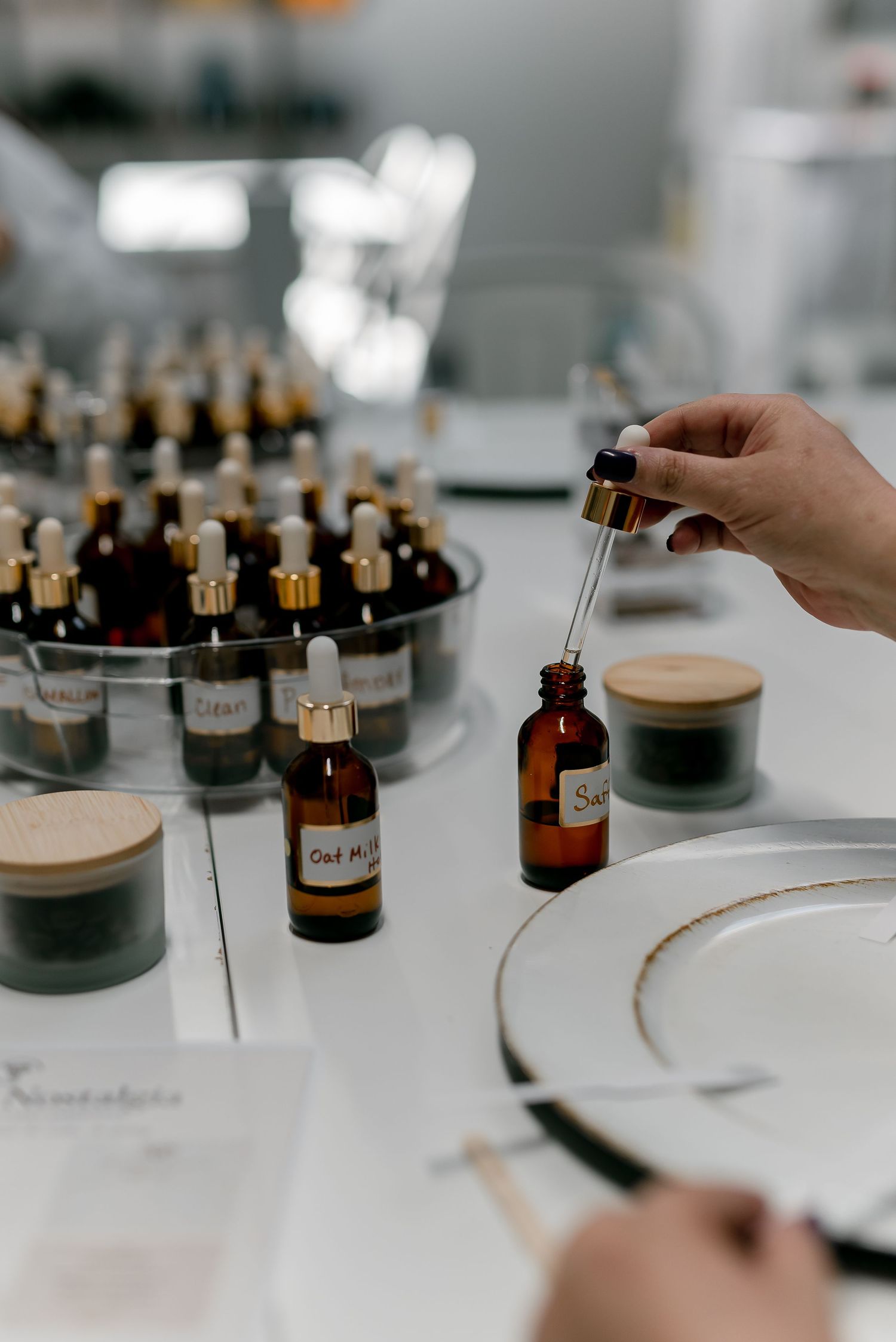 Person using a dropper bottle to sample essential oils at a perfume blending workshop with labeled amber bottles.