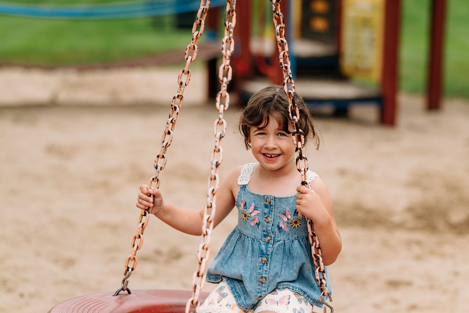 A series of photos showing someone happily swinging on a playground chain swing in denim overalls.