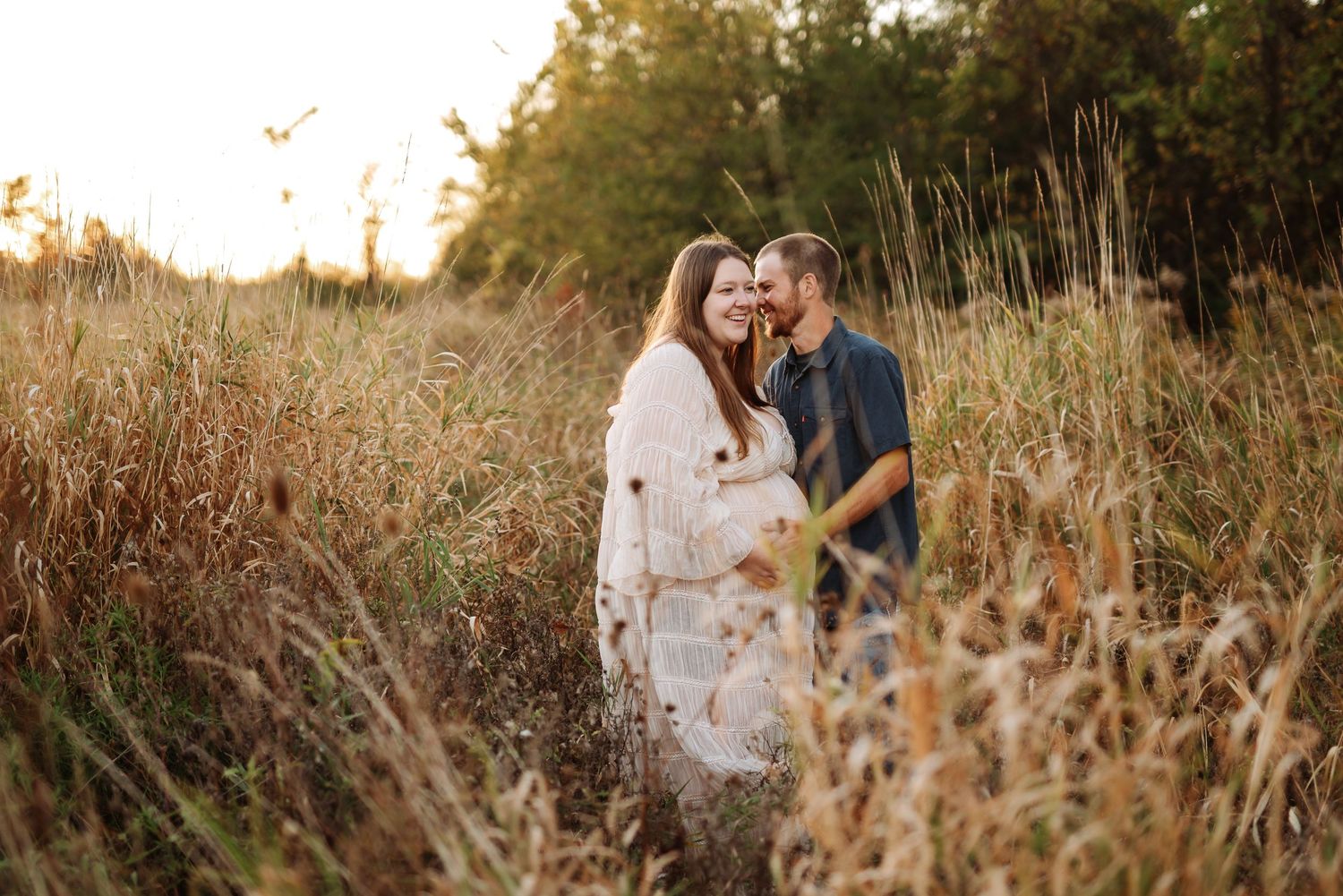 A couple embraces in a golden field during sunset creating a romantic silhouette against the warm evening light.